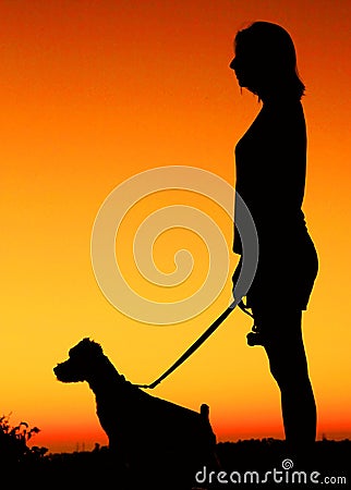 Young women watching the sunset with dog.