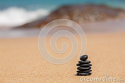 Zen stones jy on the sandy beach near the sea.