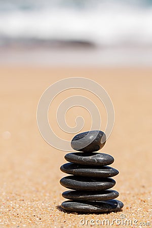 Zen stones jy on the sandy beach near the sea.