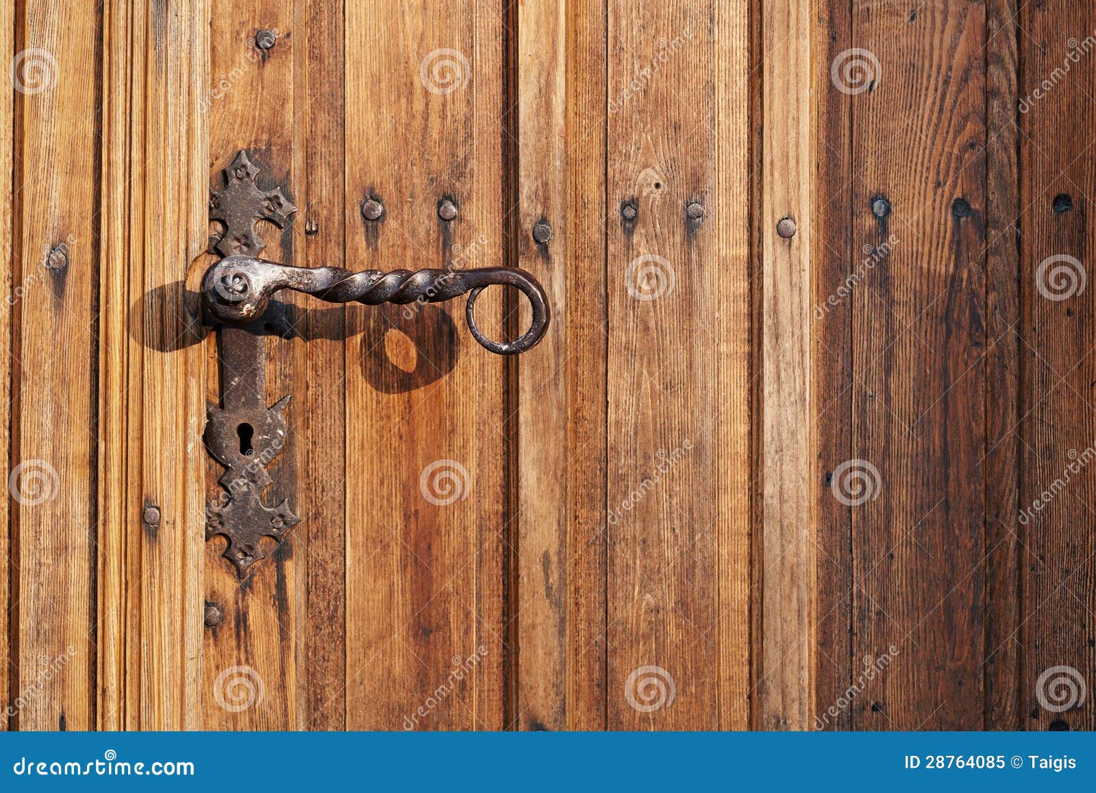 Ancient rusty church door handle on brown old wooden door.