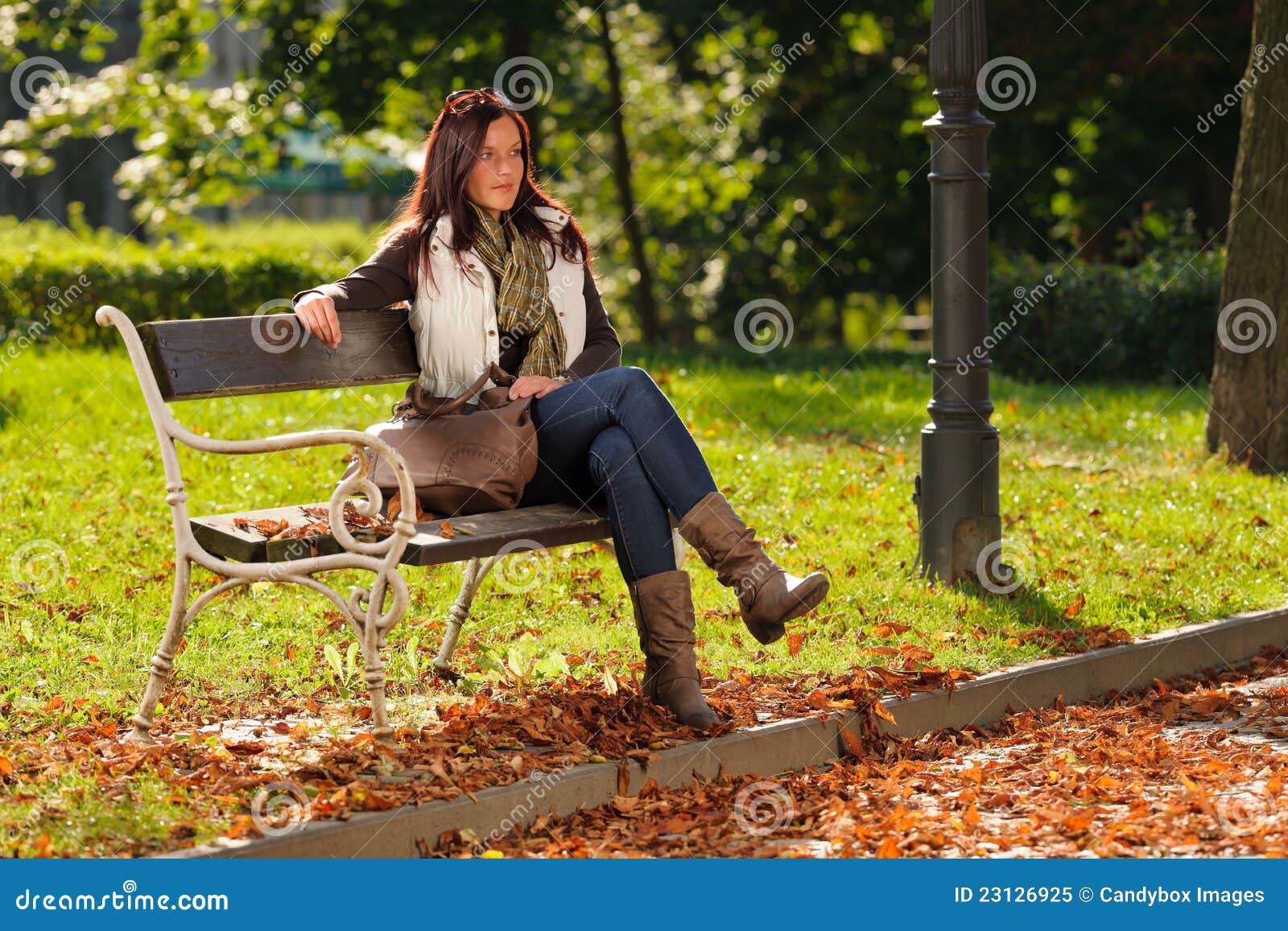 Autumn fashion outfit attractive woman sitting on park bench sunset.