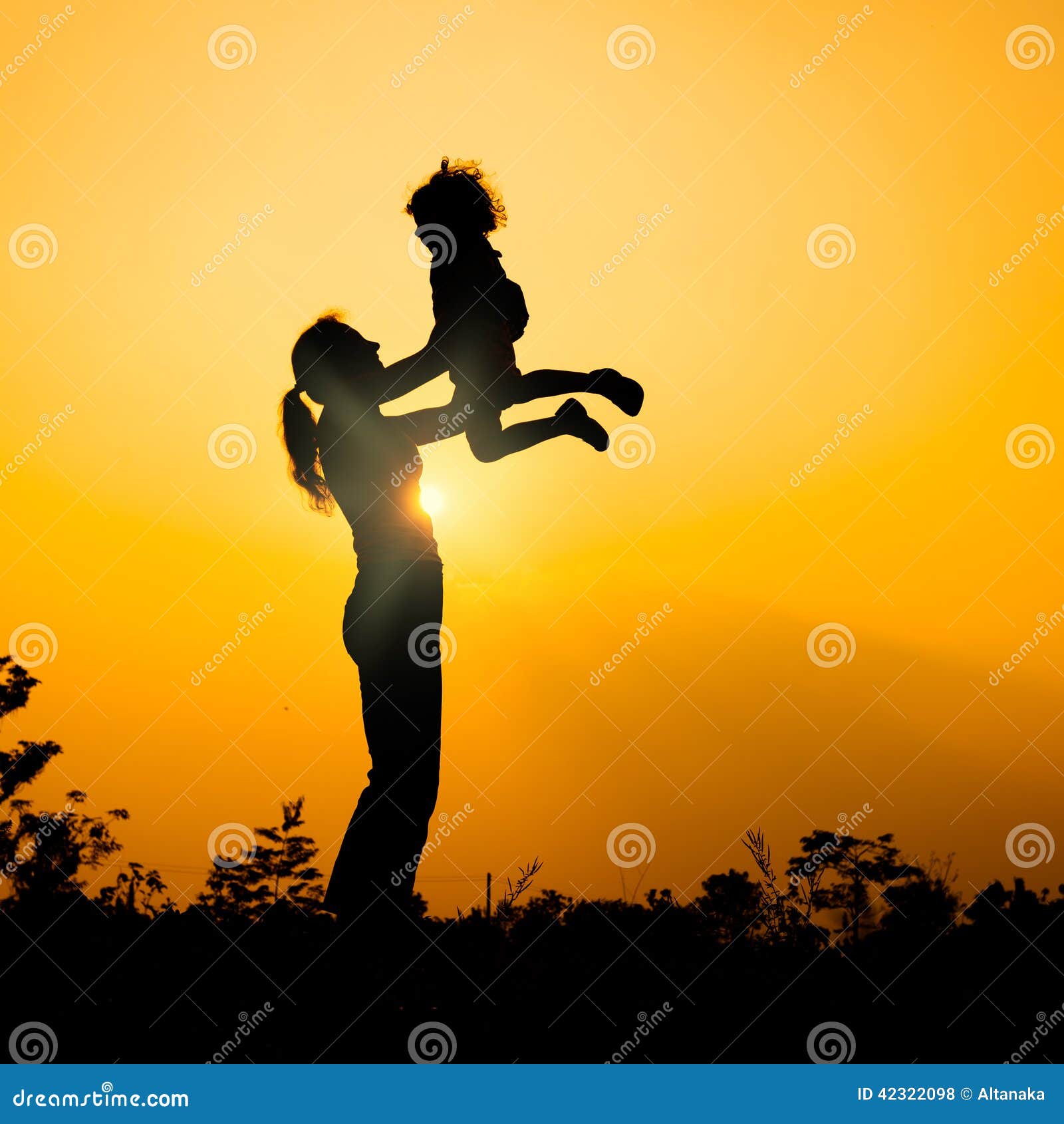 使用户外在日落背景母亲的剪影和儿子.
