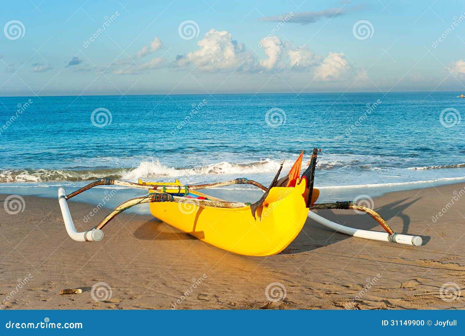 Traditional indonesian fishing boat on Bali ocean beach at sunset.