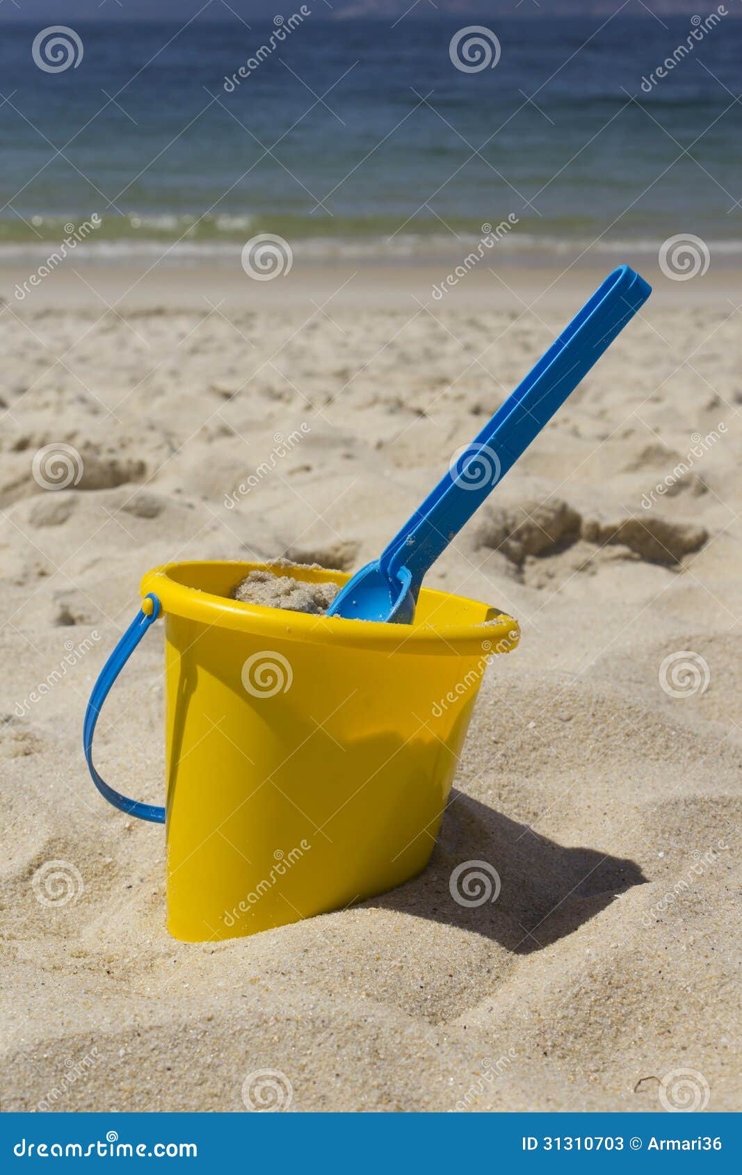 Picture of a bucket with his shovel in the sand at the beach.