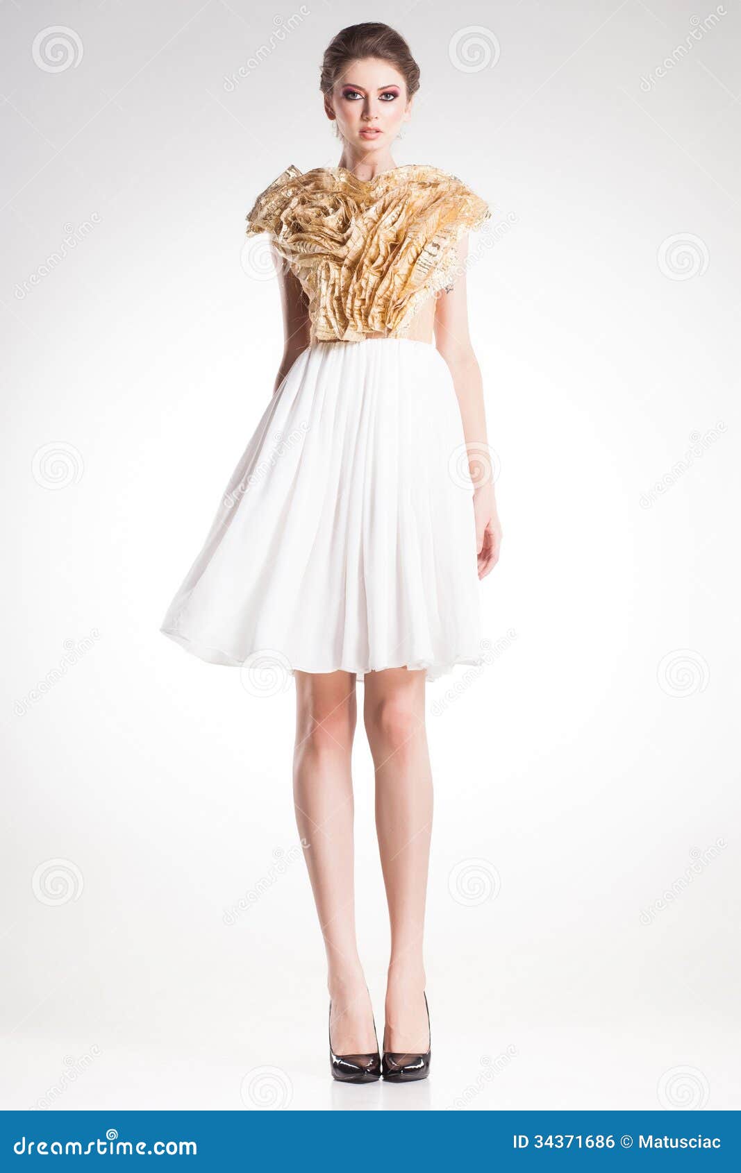 Beautiful woman model posing in elegant gold and white dress in the ...