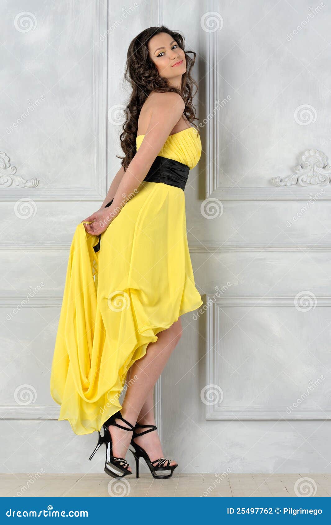 Portrait of the beautiful woman in yellow evening dress. Studio photo.