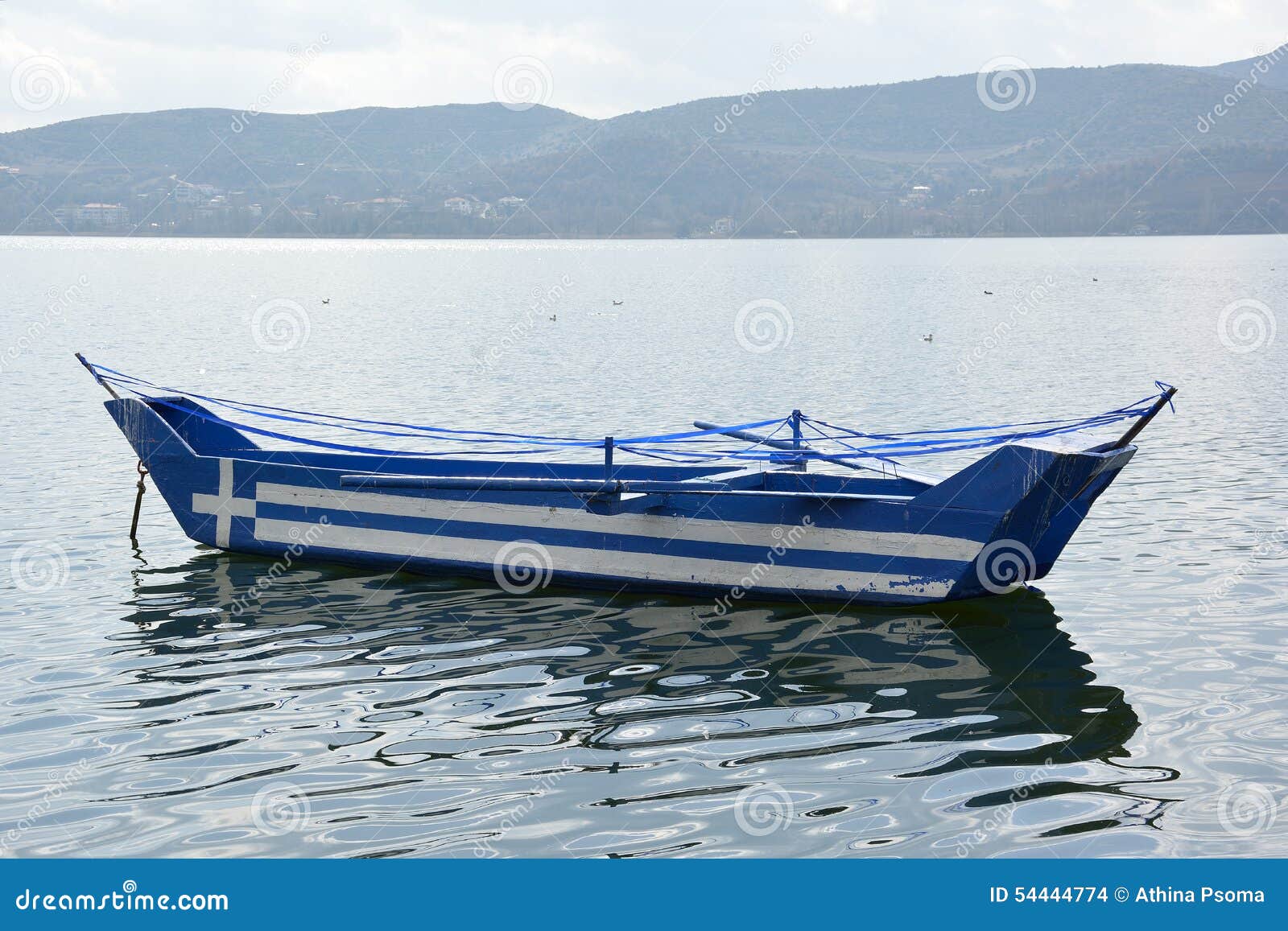  fishing boat, with greek flag painted on it, floating on lake waters
