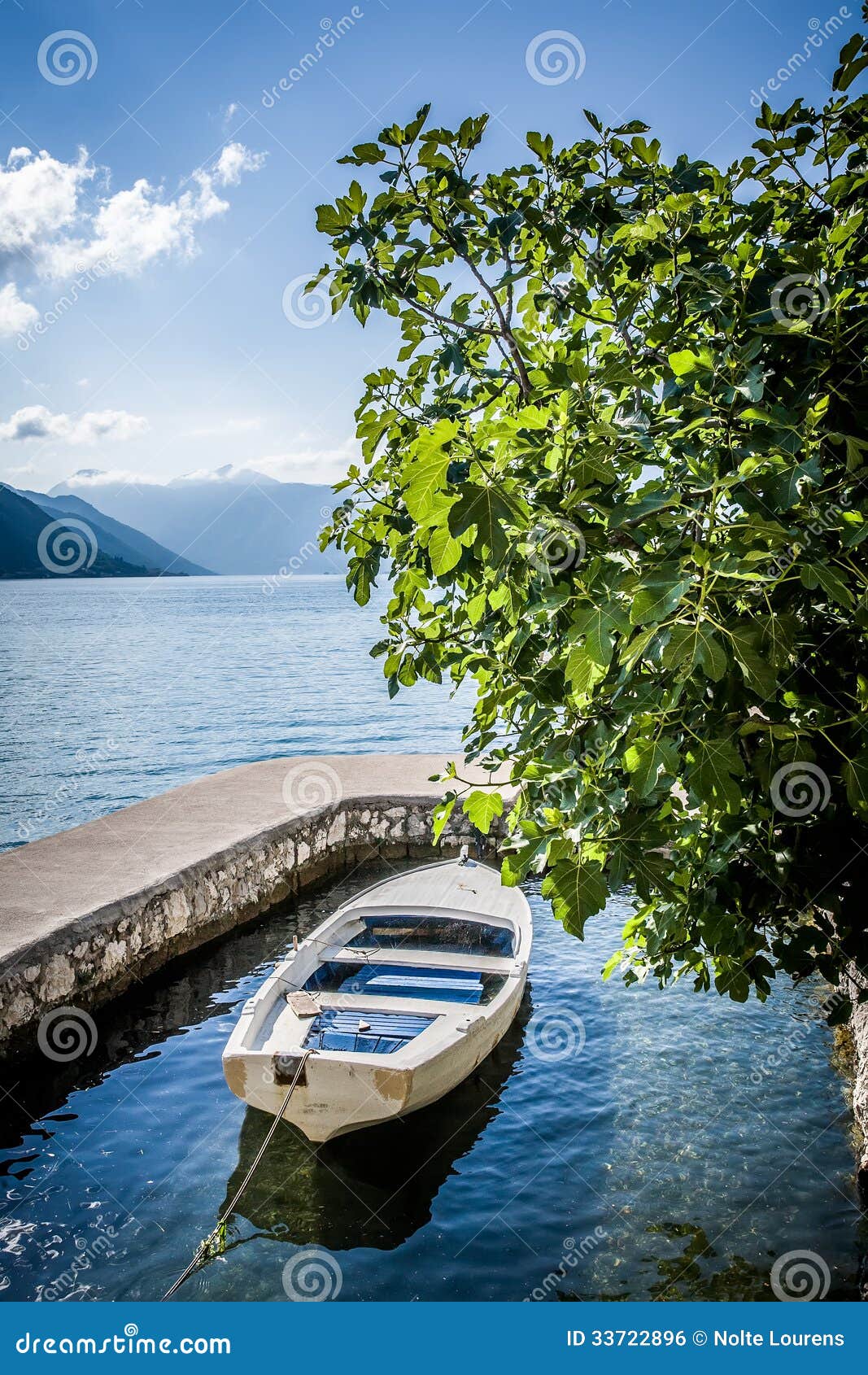 Image of a white row boat tied down in a private old stone dock with a 