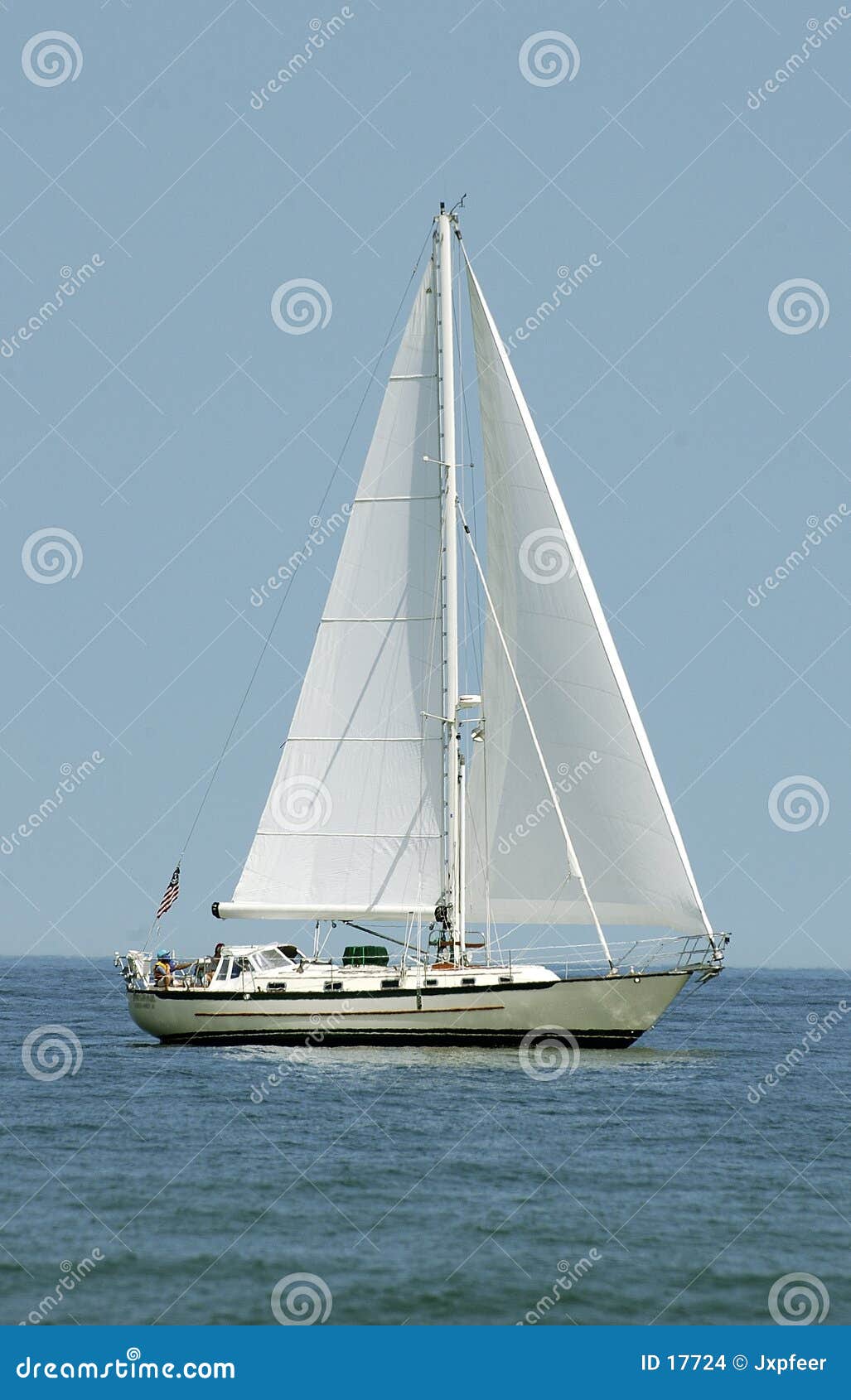 white sailboat with sails deployed, on the ocean. crop is vertical.