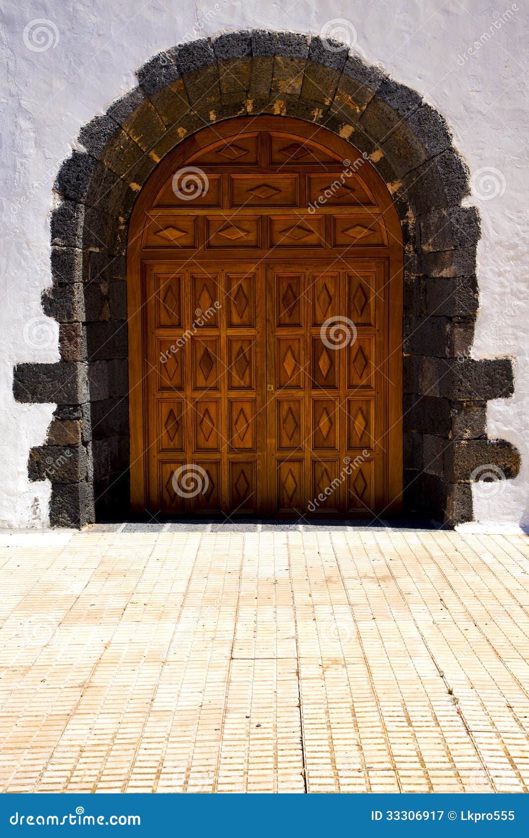 Brass brown knocker in a brown closed wood church door and white wall 