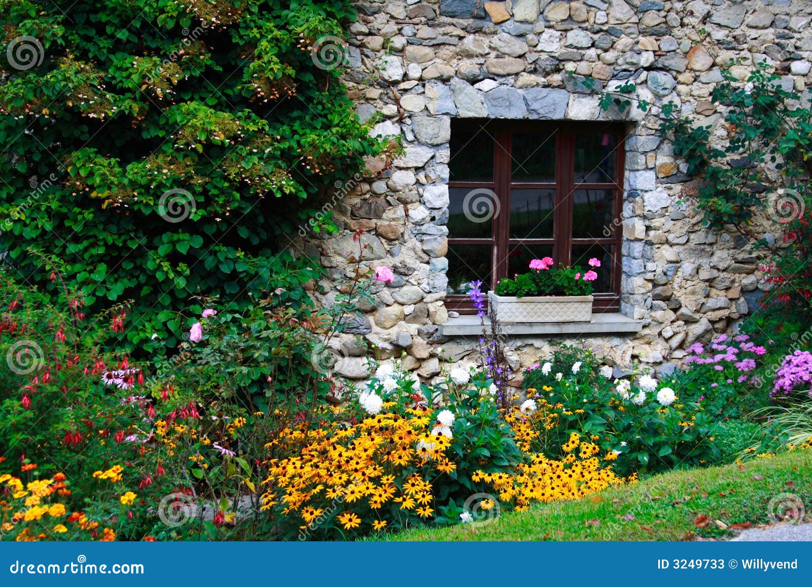jardim pedras e flores:Indicador de uma casa pedra-construída em um jardim florescido rural. jardim pedras e flores:Indicador de uma casa pedra-construída em um jardim florescido rural.