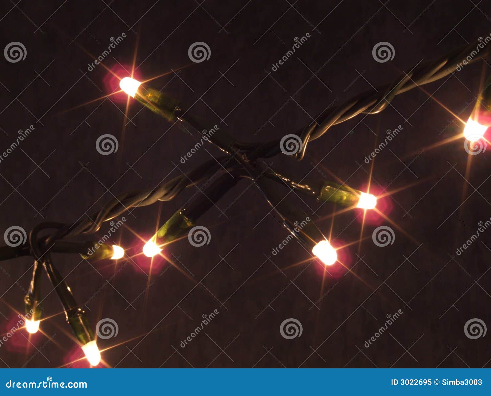 strand of lit Christmas lights against a dark background. Lights ...