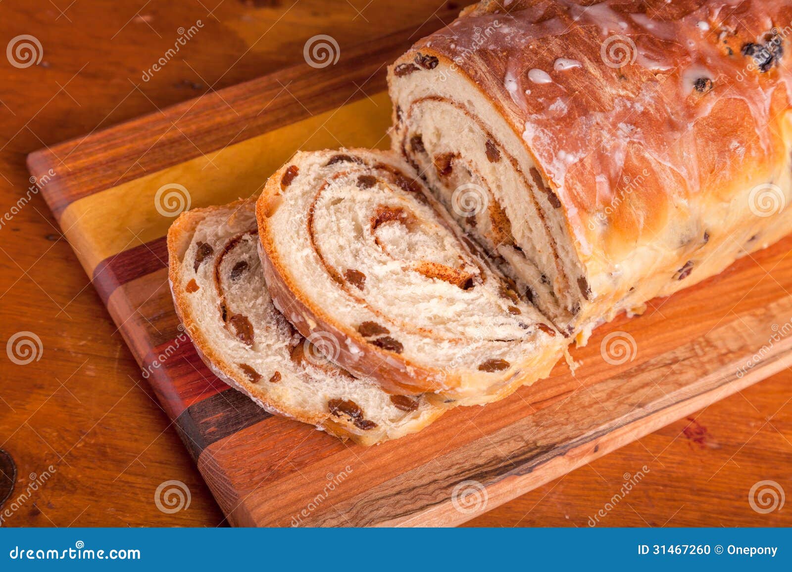 Homemade rolled cinnamon raisin bread on a wooden cutting board.