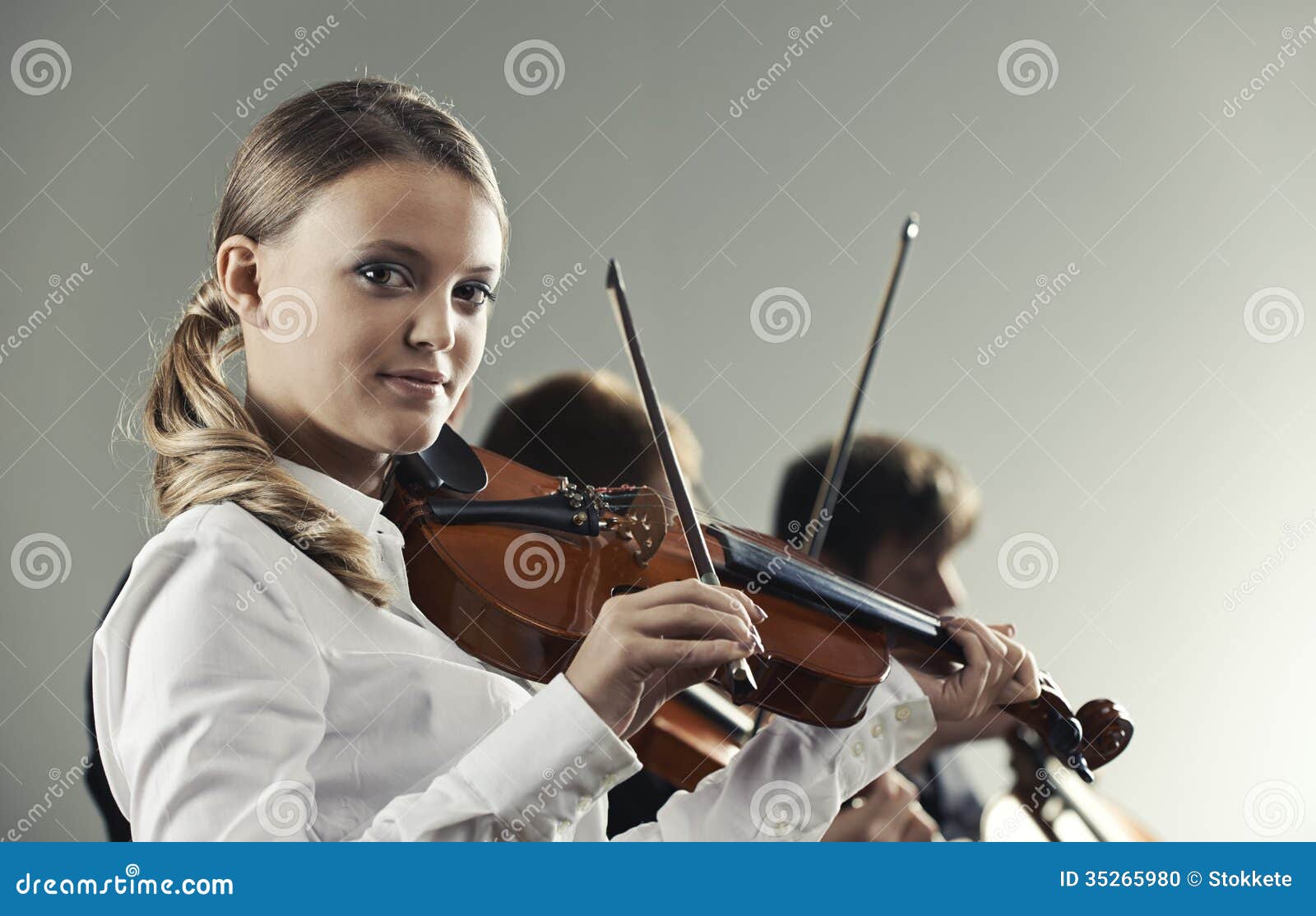 Musicians in concert, beautiful female violinist on foreground.