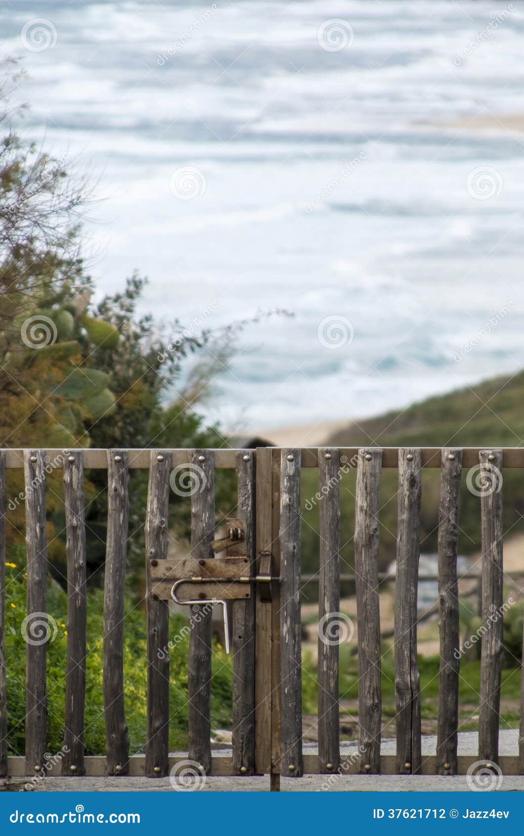 closed gate made of rough logs of wood and behind  the rough sea 