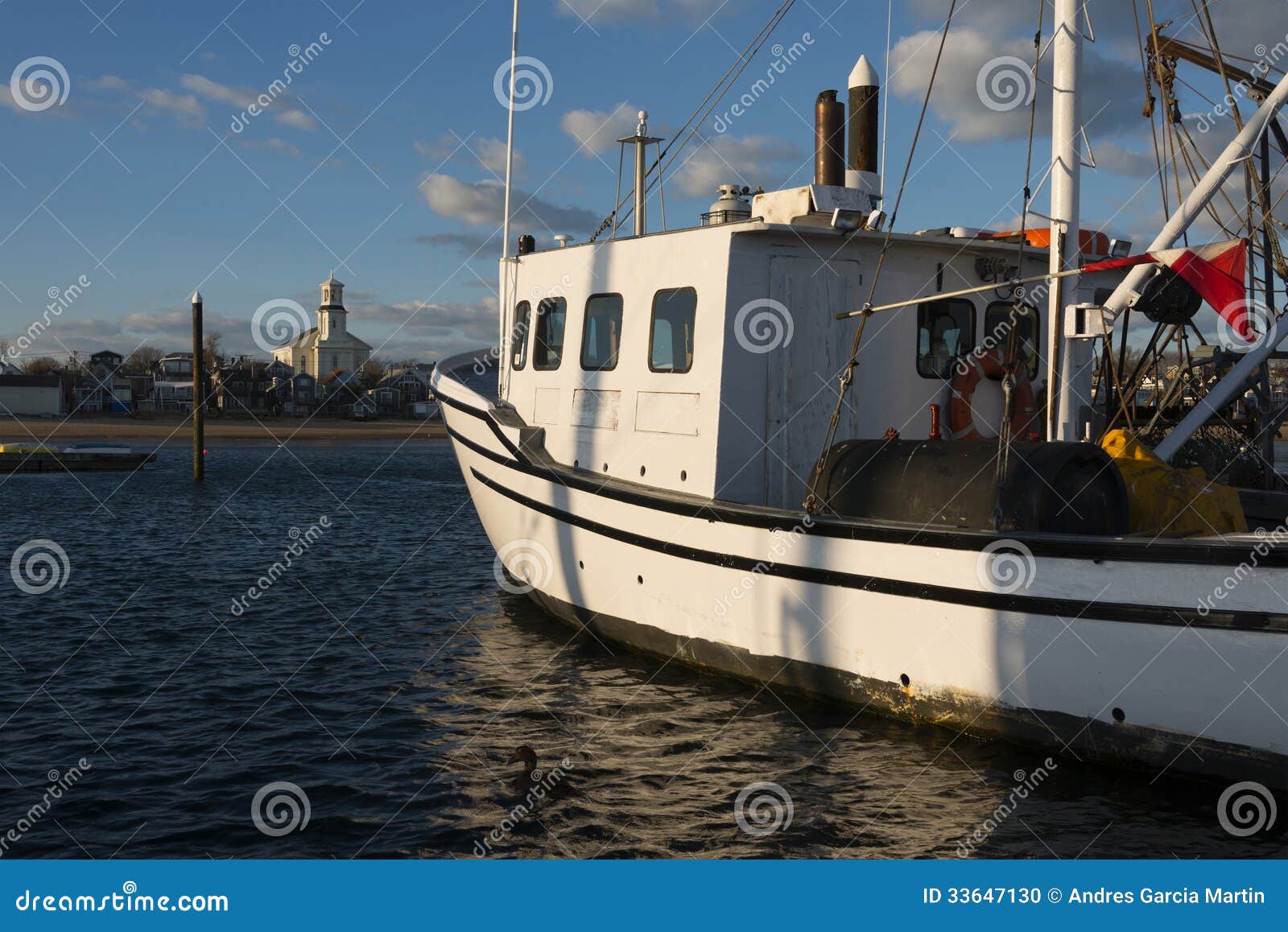 Fishing boat in Provincetown harbor at the tip of Cape Cod at sunset.