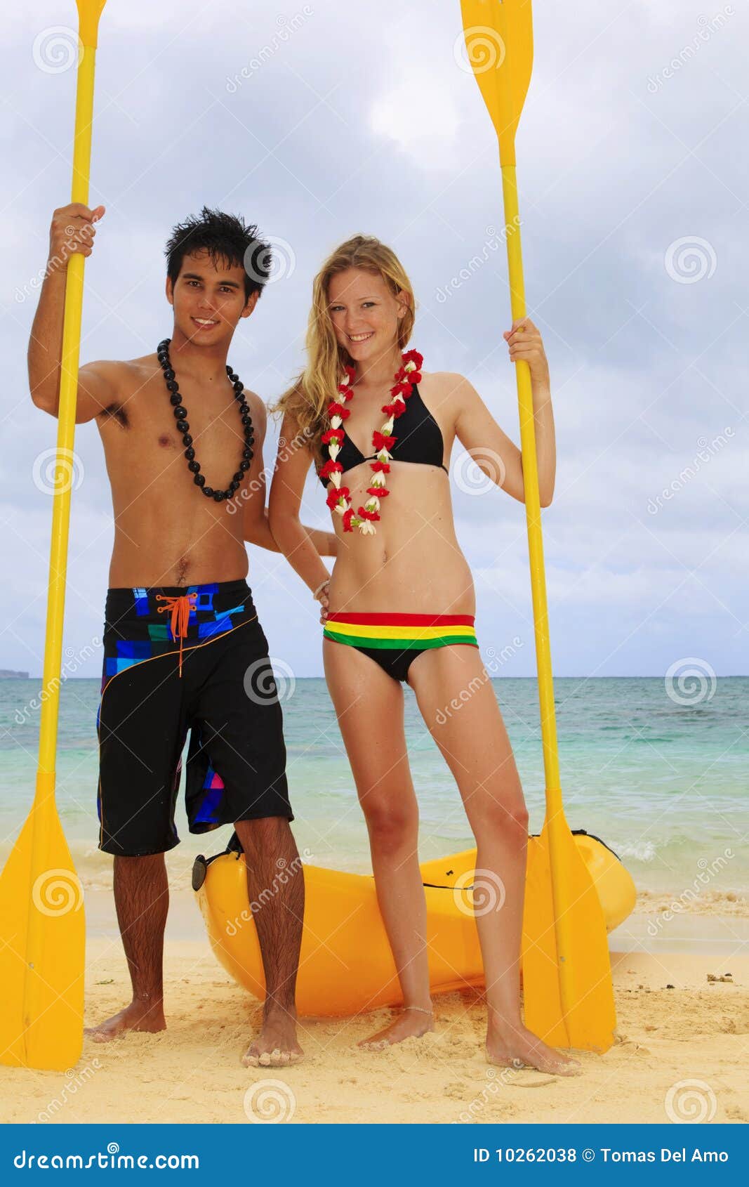 Polynesian man and a blond caucasian girl, wearing leis, stand on 