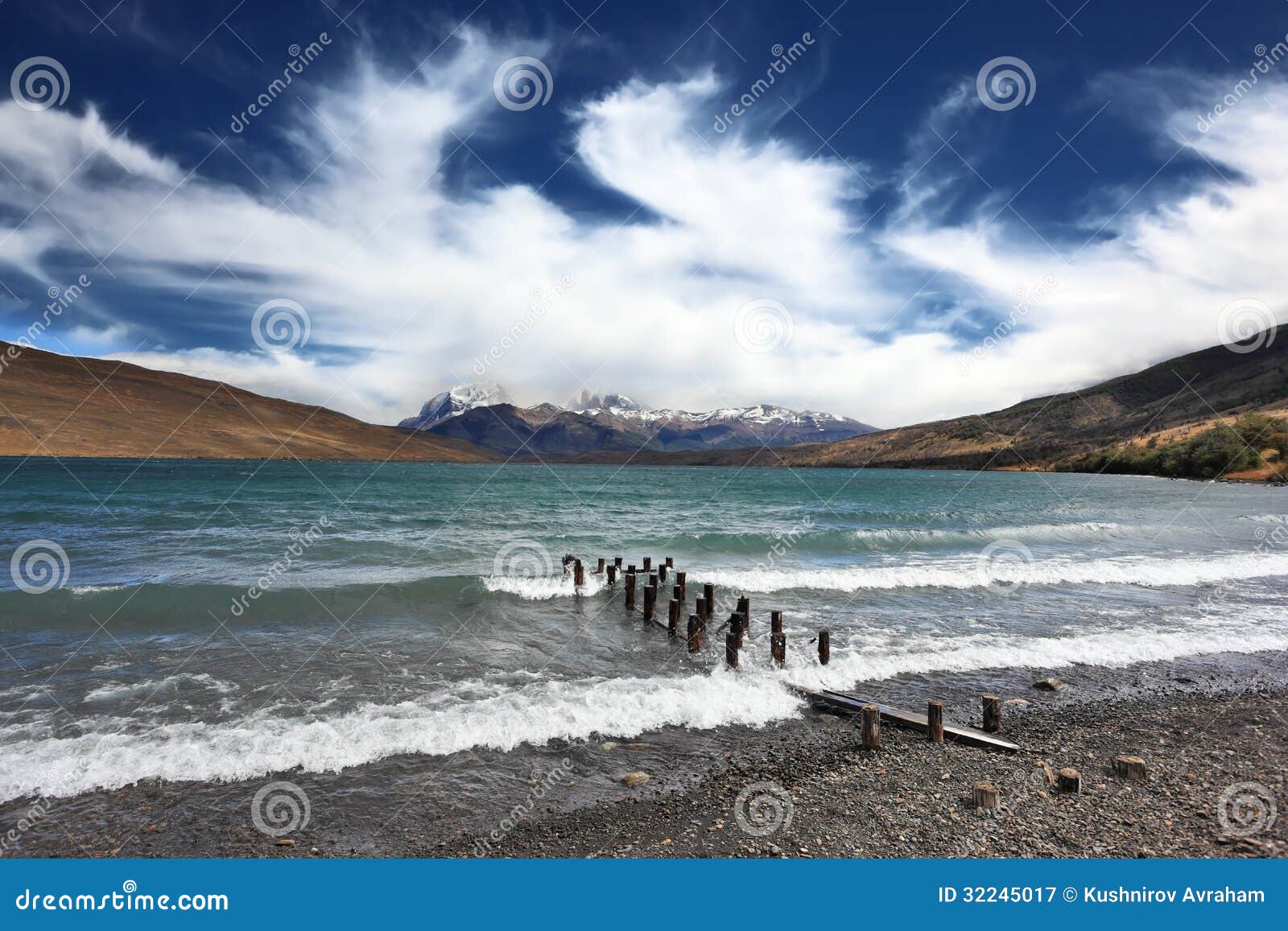 The storm on the lake. Boat dock poured foaming waves. The mountains 