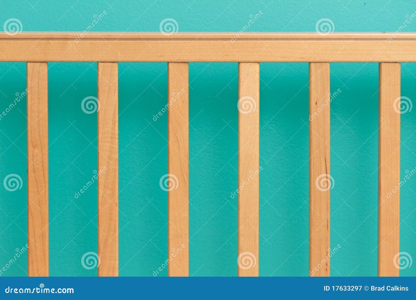Side railing of baby's crib against turquoise wall.