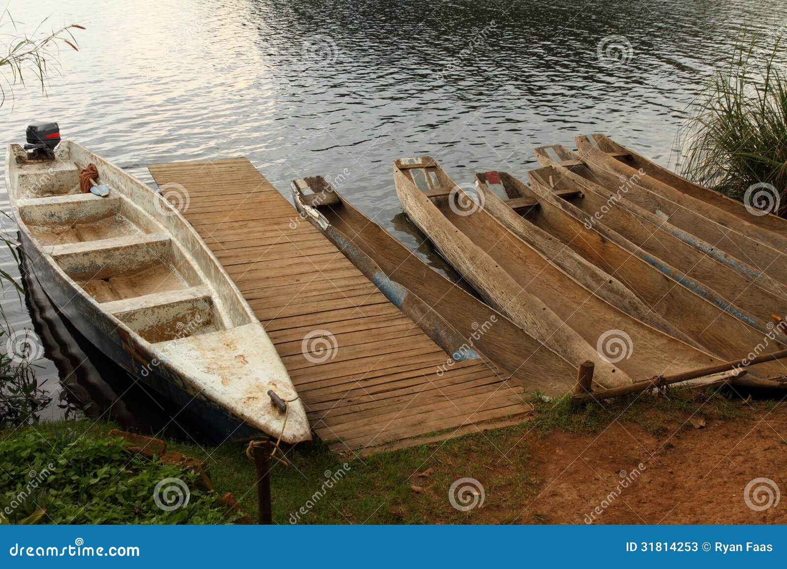  Dugout canoes and one boat launch waiting on a lake shore at the dock