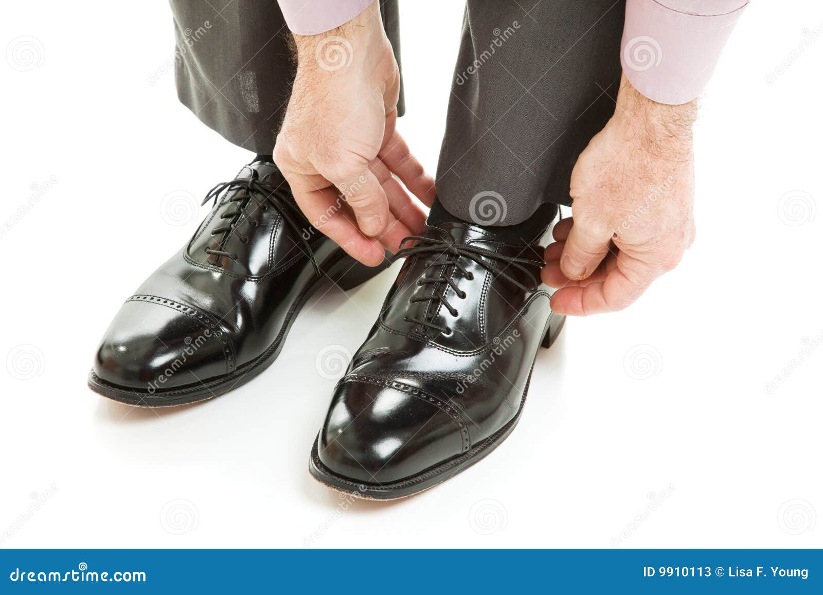 ... ties his shiney new black leather business shoes. Isolated on white