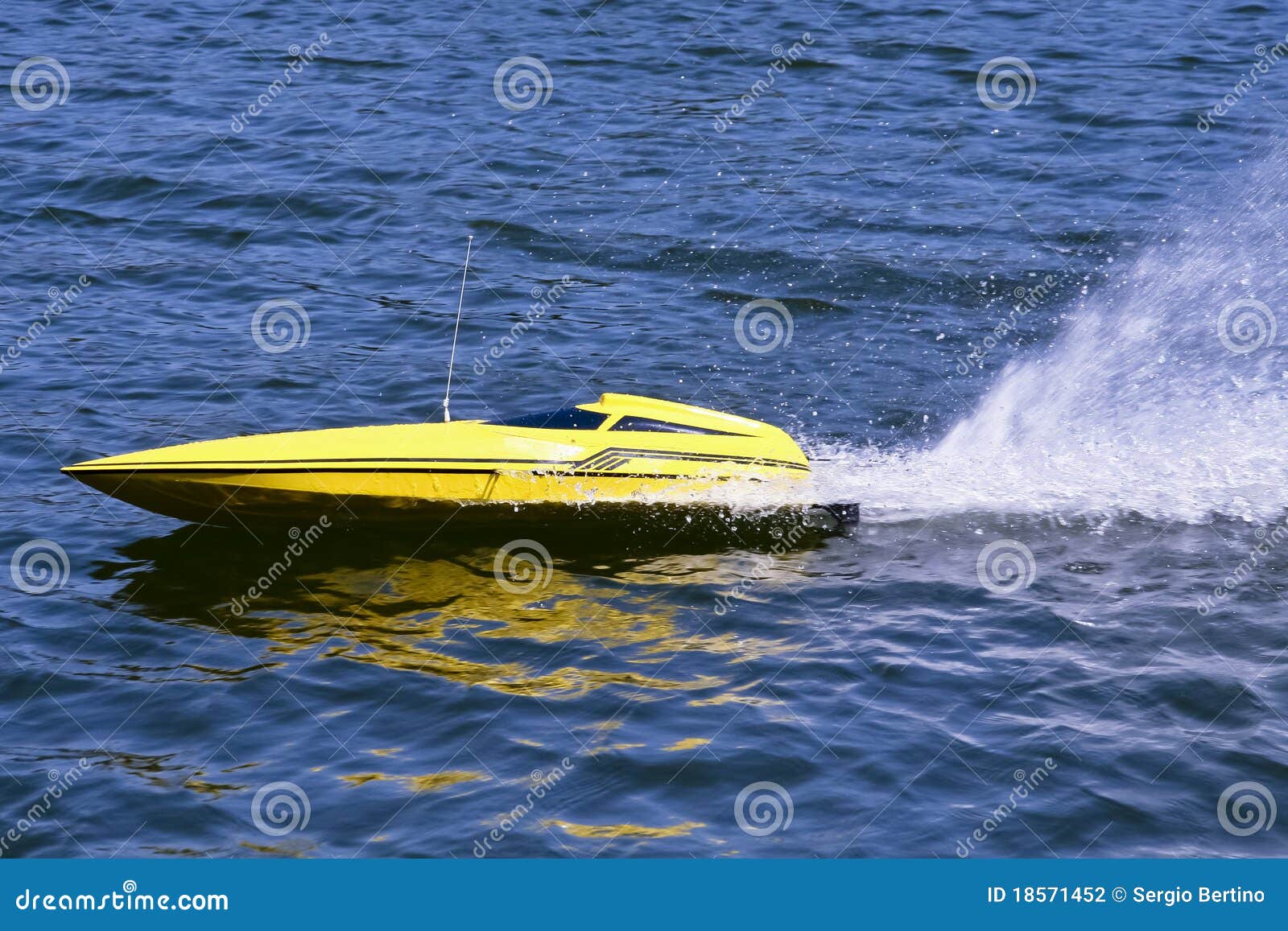 Yellow electric model boat skimming across the water leaving spray in 