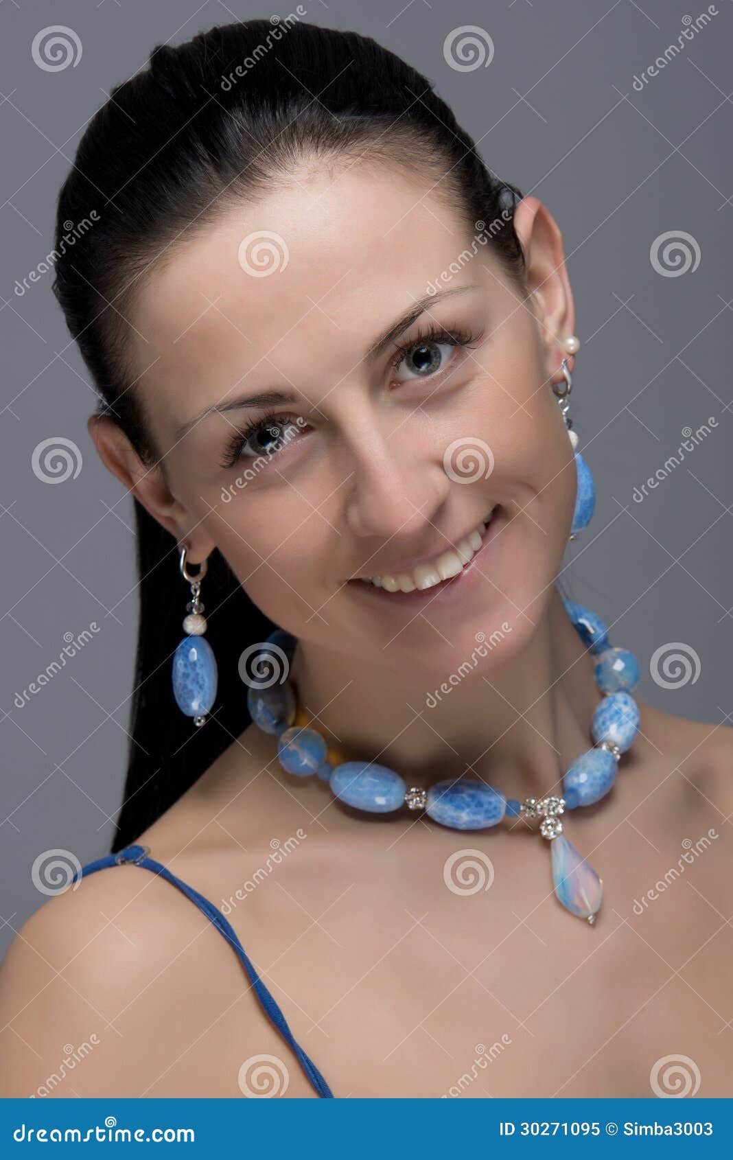 Feche acima do retrato da mulher alegre nova que veste brincos e a colar vívidos da luz - pedras azuis. Cara natural da beleza. Foco seletivo. - feche-acima-do-retrato-da-mulher-alegre-nova-que-veste-brincos-e-colar-v%25C3%25ADvidos-da-luz-pedras-azuis-cara-natural-da-beleza-foco-30271095