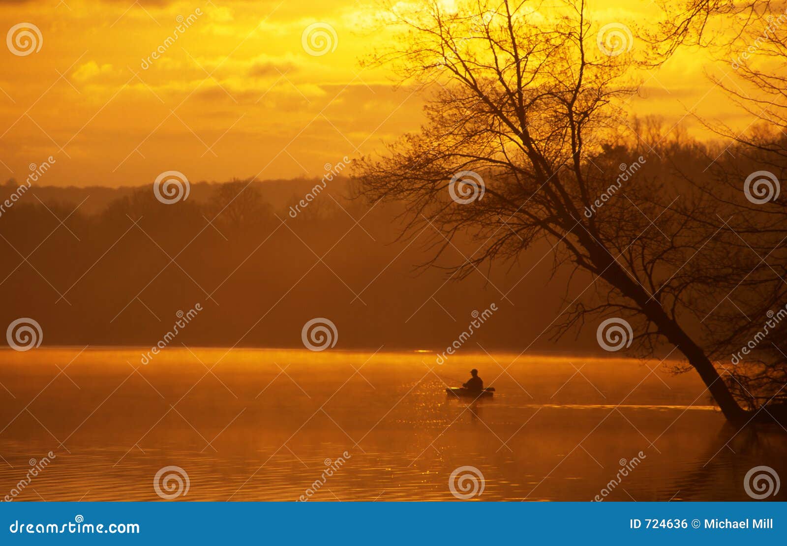 An angler fishing from a kayak on a beautiful lake at sunrise.