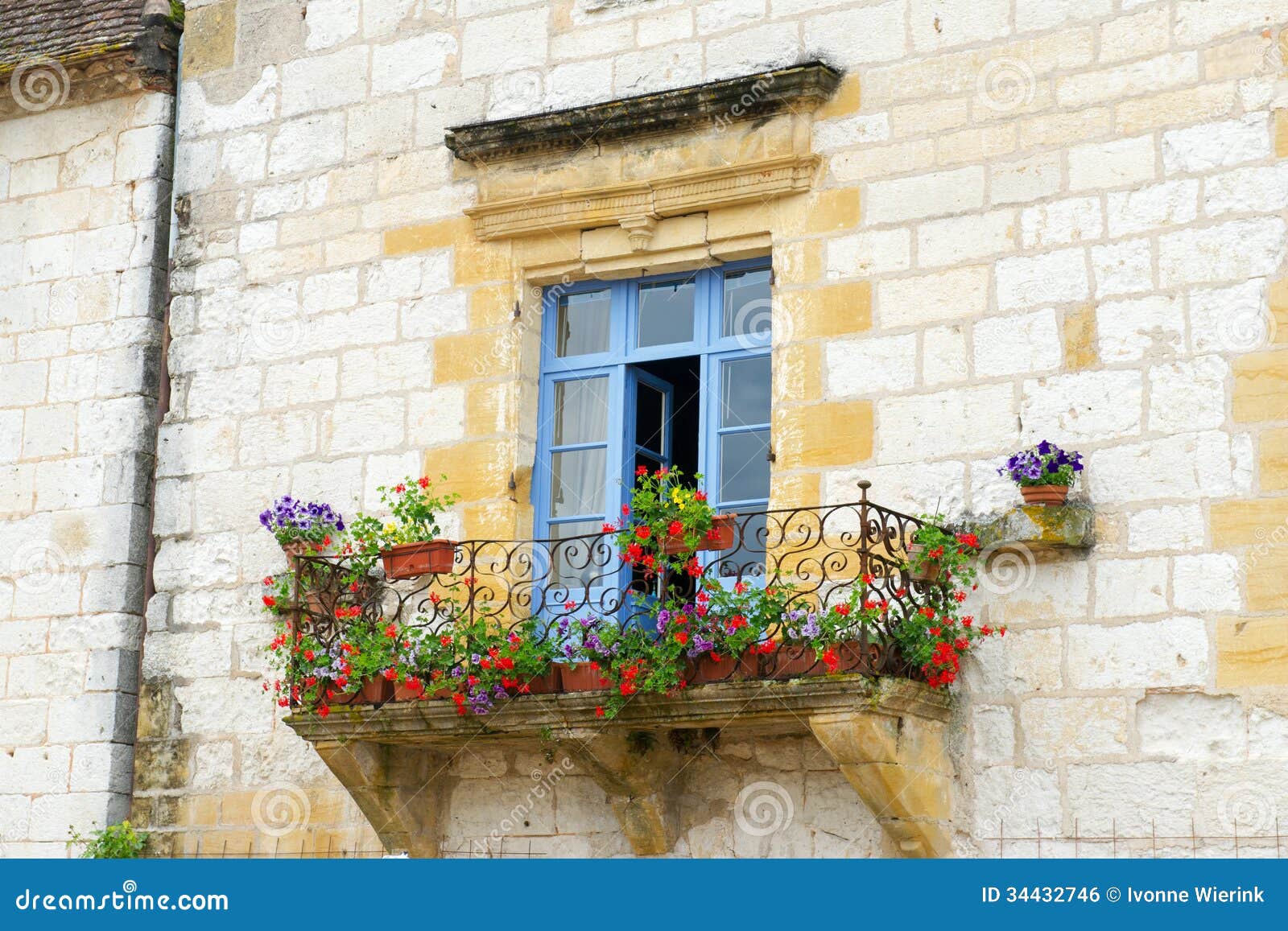 French balcony with flowers and blue window.