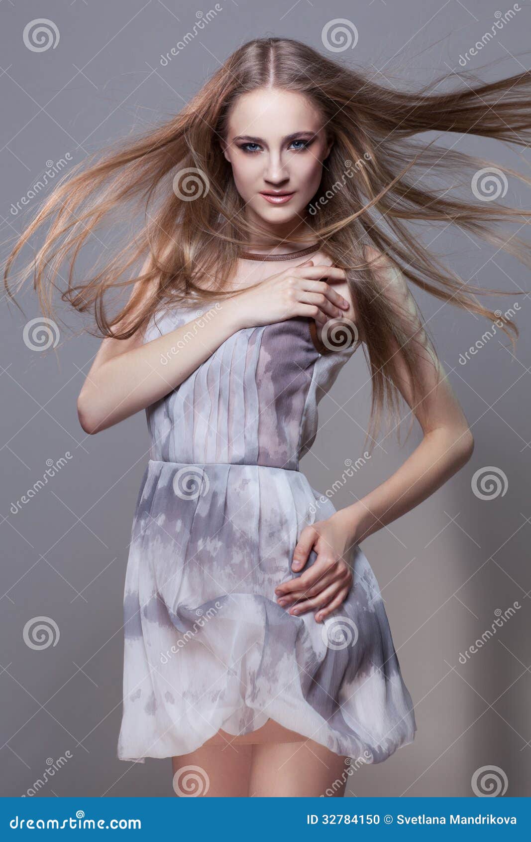 ... standing beautiful girl with flying hair in fashionable short dress