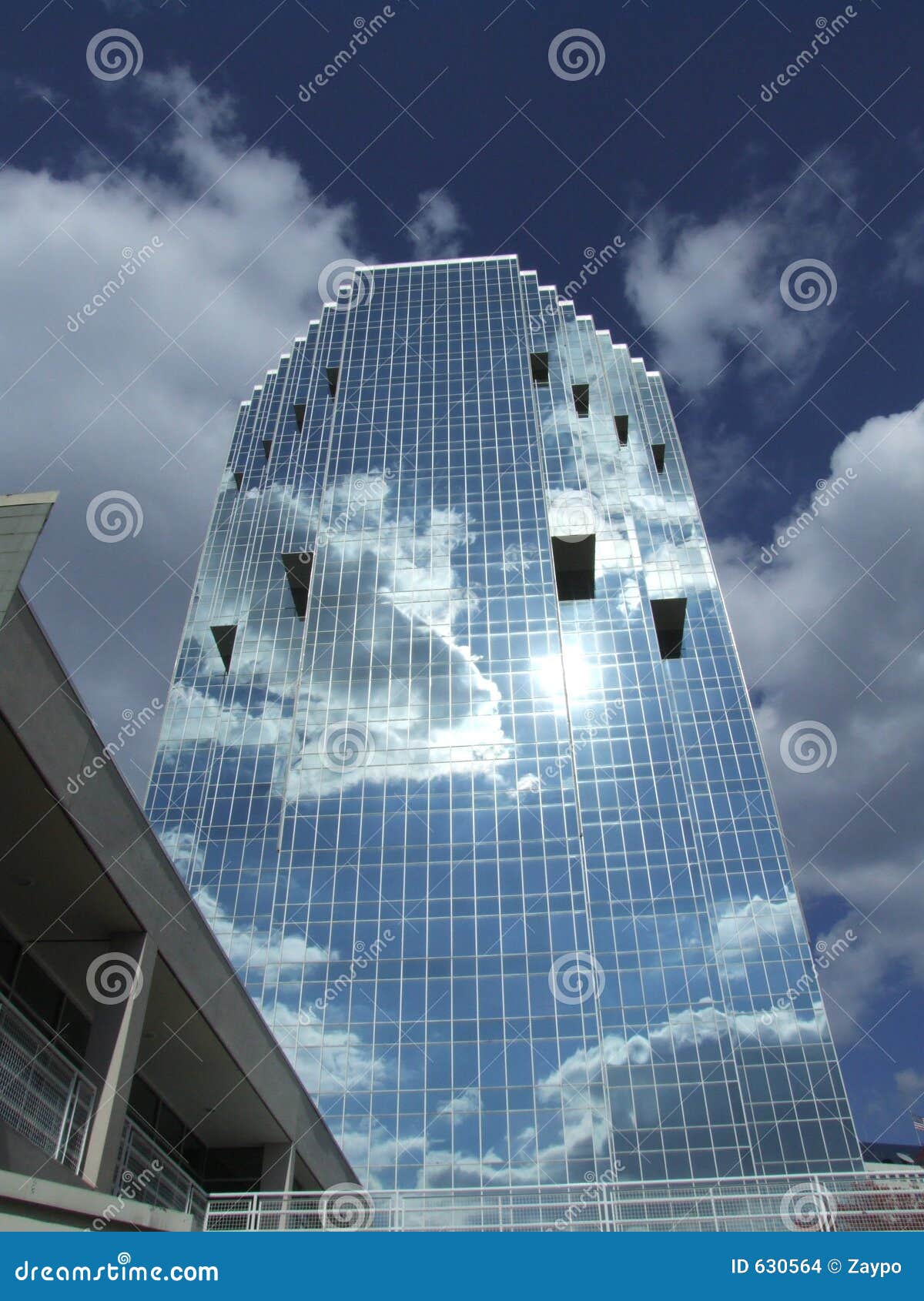 glass office building with the clouds and sun reflecting on the 