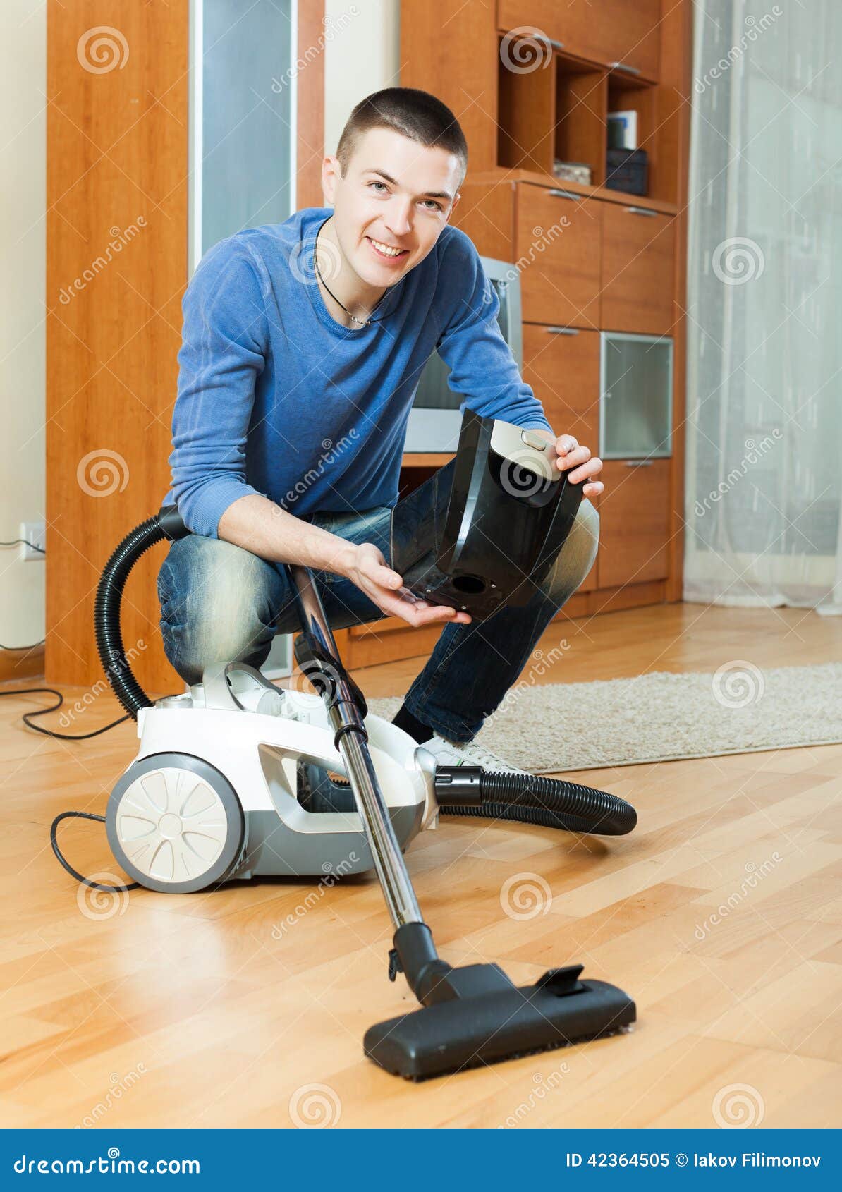 Guy Vacuuming With Vacuum Cleaner On Parquet Floor In