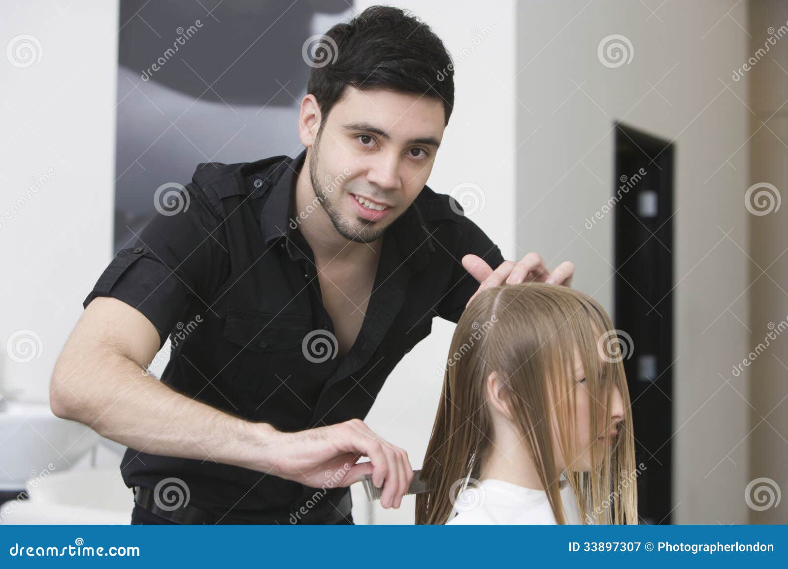 Portrait of male hairstylist combing clients hair at beauty salon.