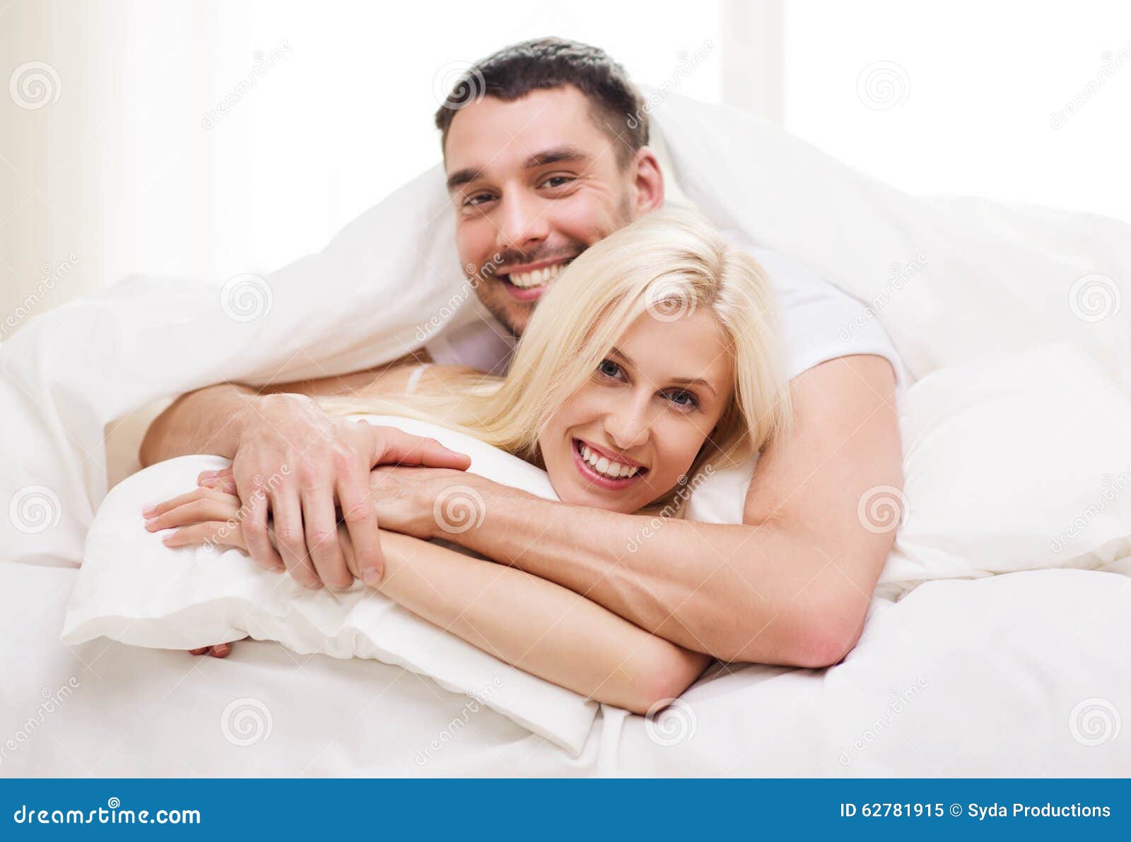 Happy Couple Lying In Bed And Hugging At Home Stock Photo - Image: 62781915