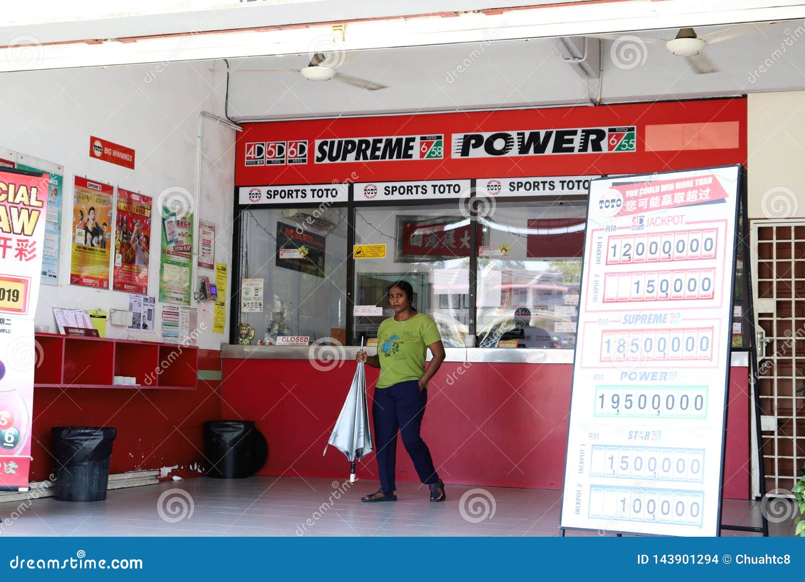 indian-lady-walking-out-sports-toto-outlet-ticket-counters-signboard-posters-berjaya-malaysia-143901294.jpg