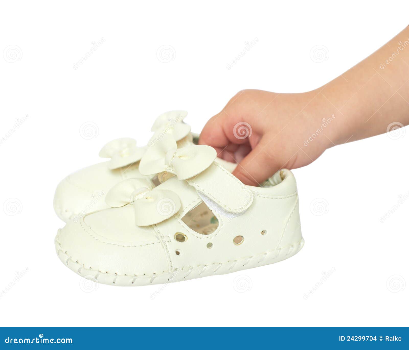 Kids hand holds small white baby shoes, studio shoot isolated on white ...
