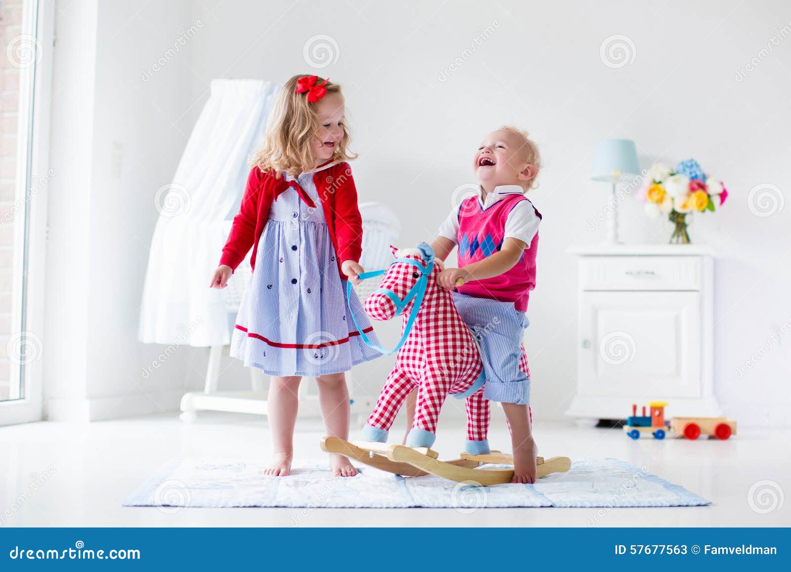 Two children play indoors. Kids riding toy rocking horse. Boy and girl 