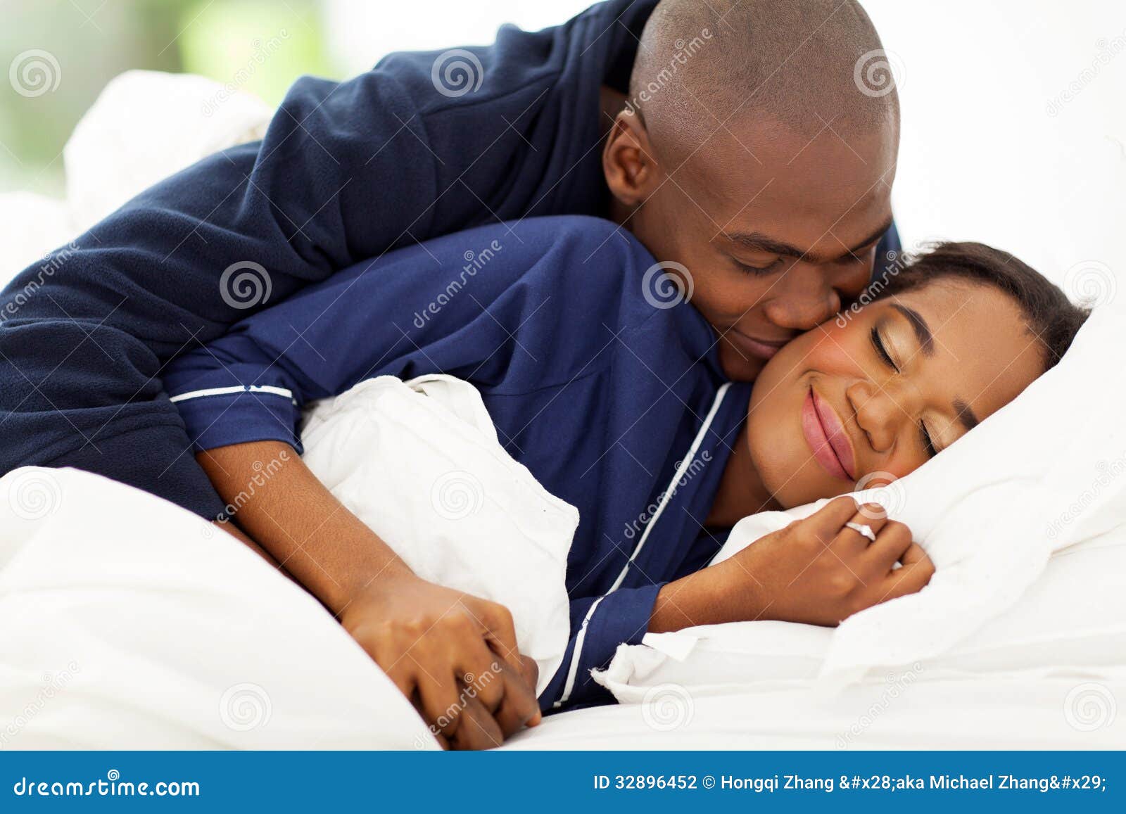 Smiling african men in bed kissing wife in bed.