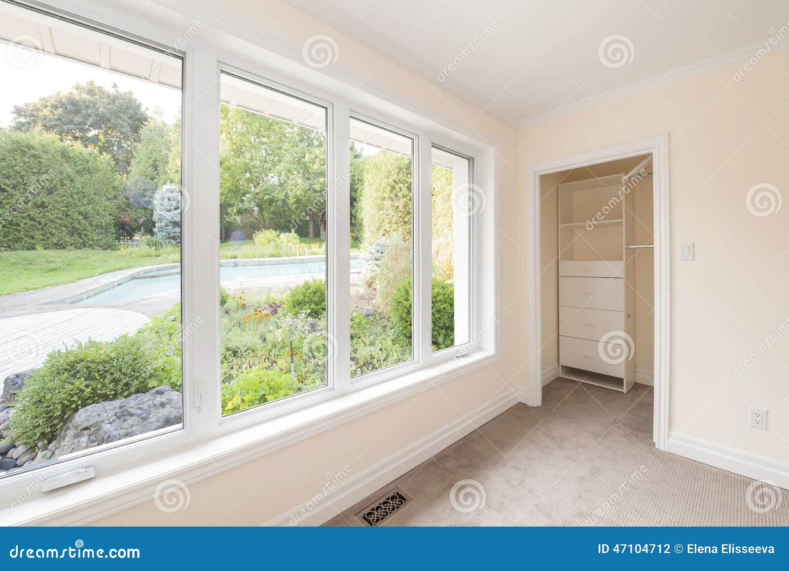 Large window in empty bedroom looking on summer backyard with garden Large window in empty bedroom looking on summer backyard with garden