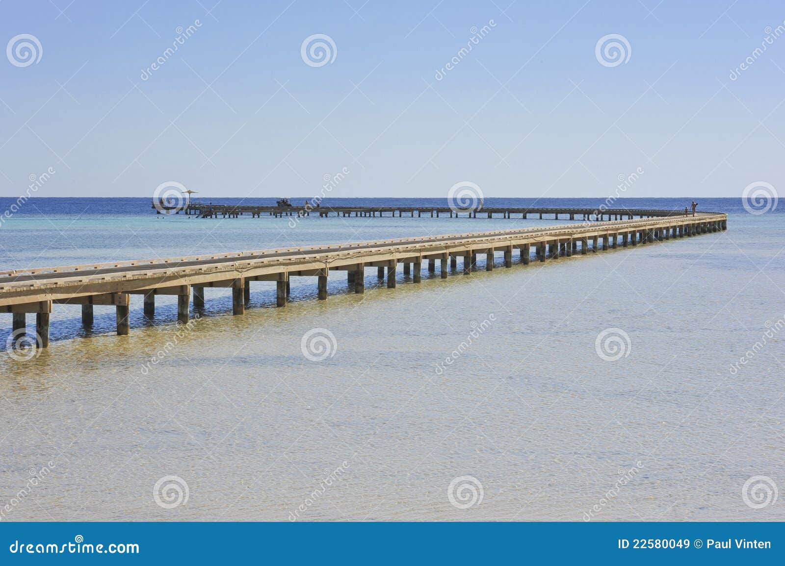 Long wooden jetty going out over a tropical coral reef.