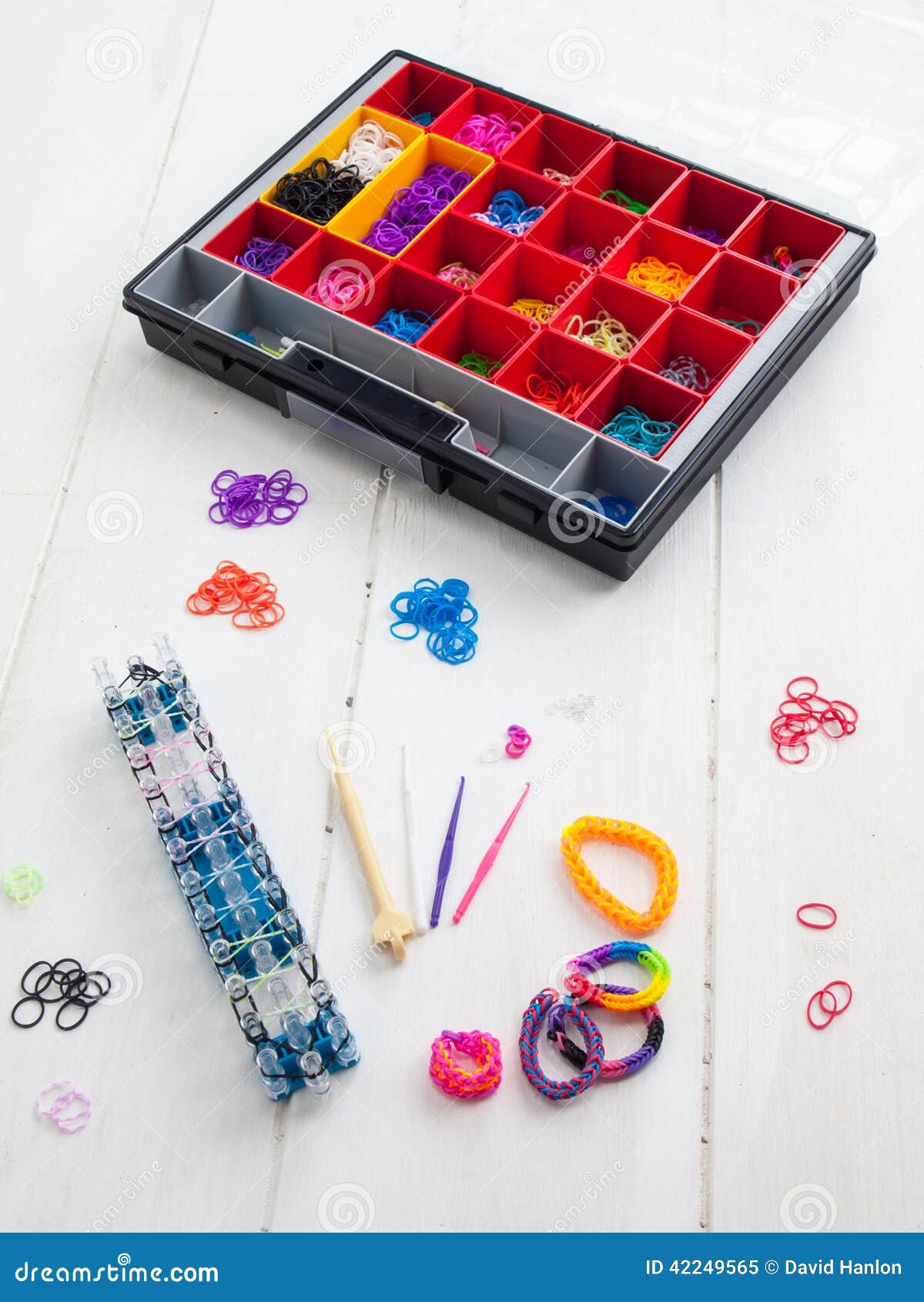  band loom , bracelets, tools and hobby box against a white table top