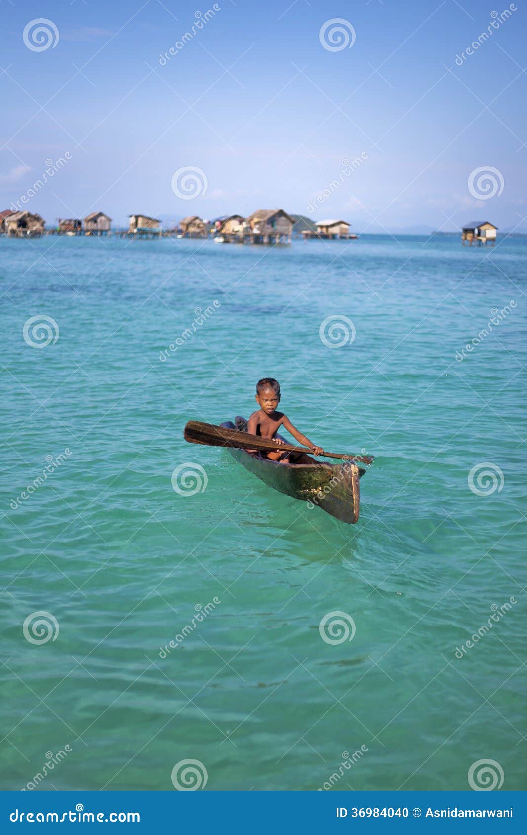 ISLAND, SABAH, MALAYSIA - MARCH 3: local sea gypsy kid paddles a boat 