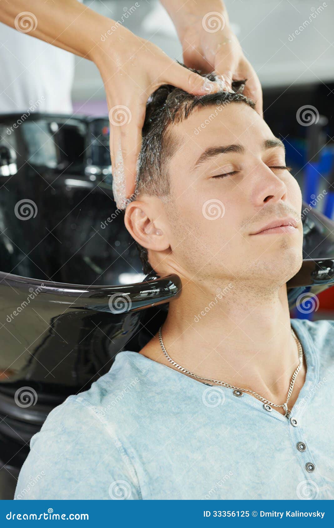 Washing man client hair in beauty parlour hairdressing salon.