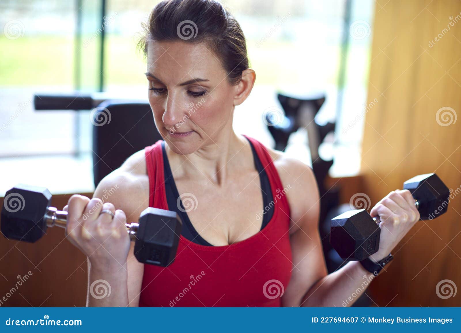 Mature Woman Exercising In Home Gym Lifting Hand Weights Stock Image