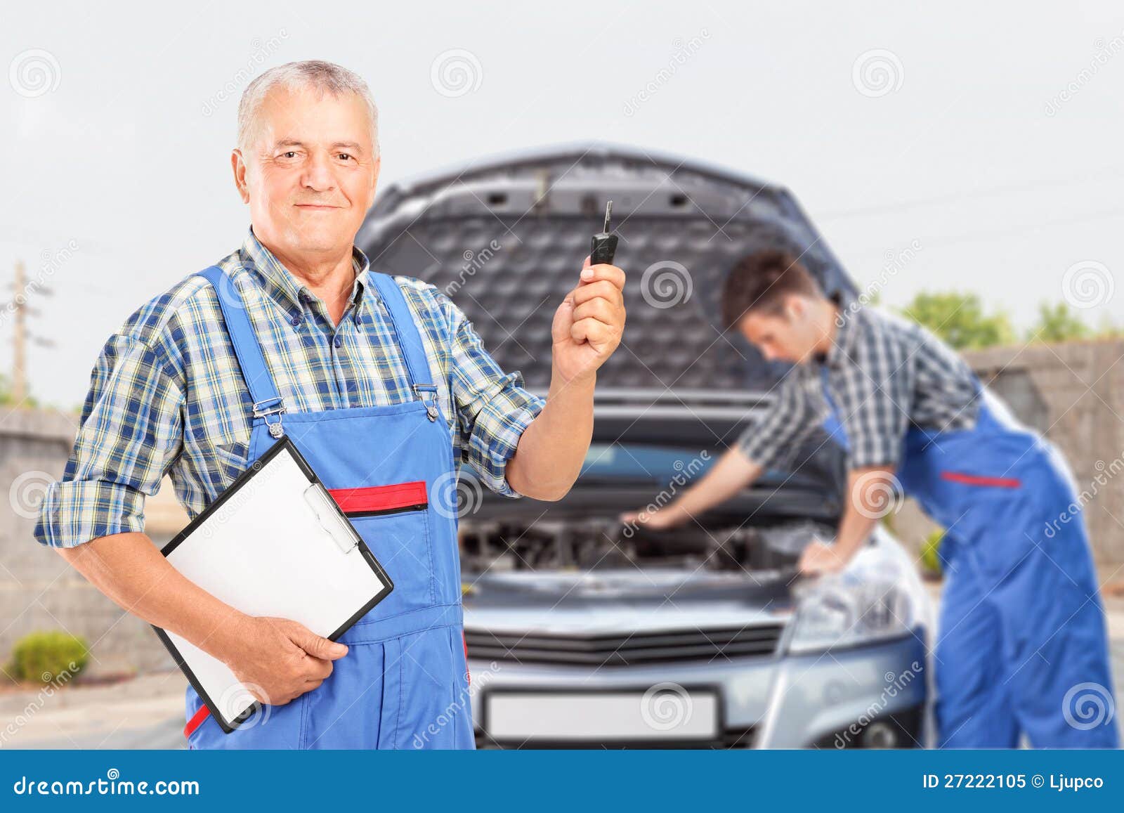 car key and another mechanic performing a car check in the background