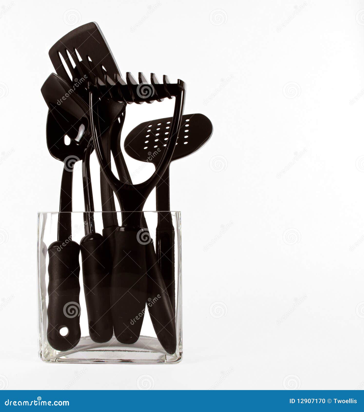 Contemporary black kitchen utensils in a clear glass vase on white.