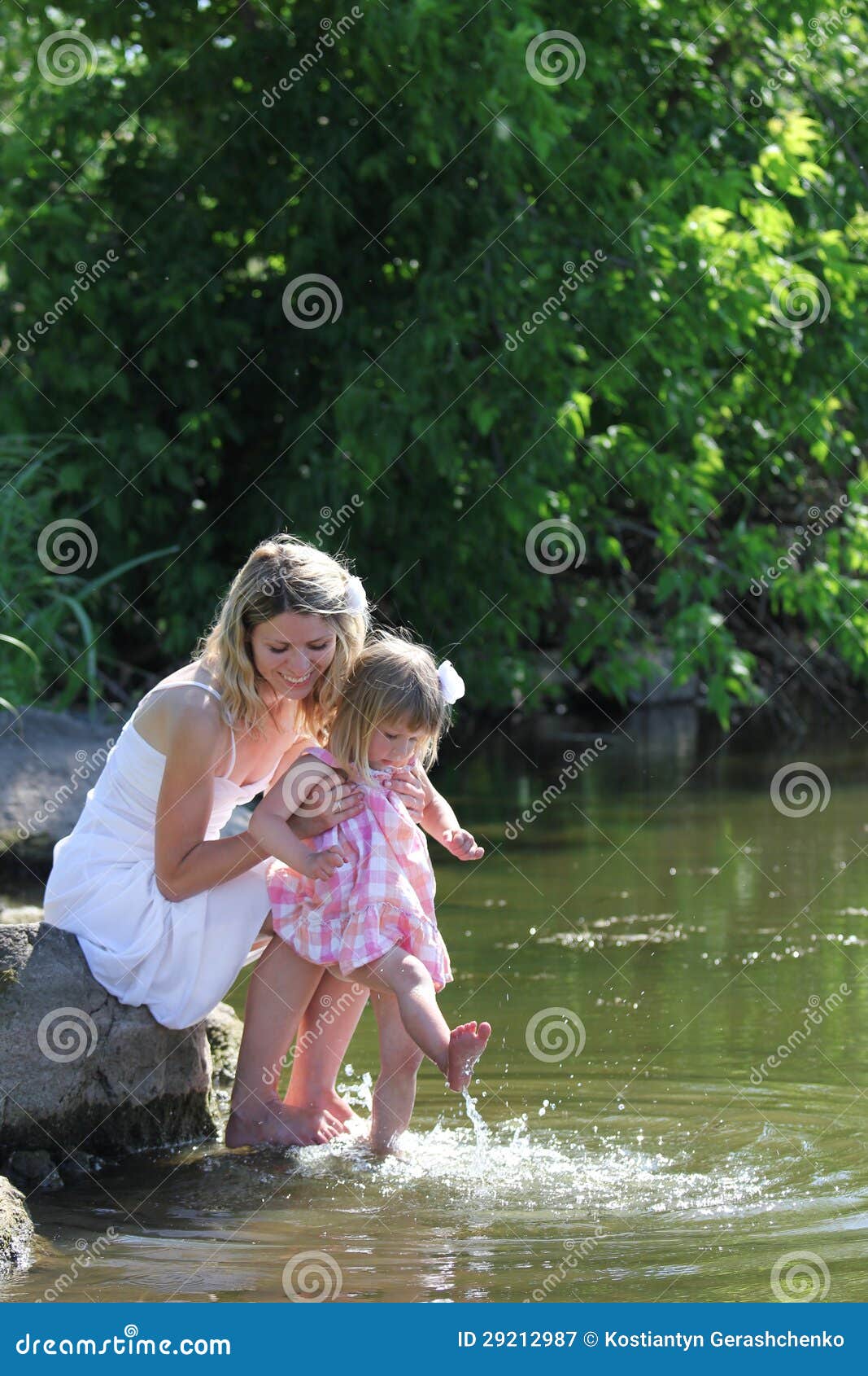 Mom And Her Little Daughter Play On The Grass Near The 
