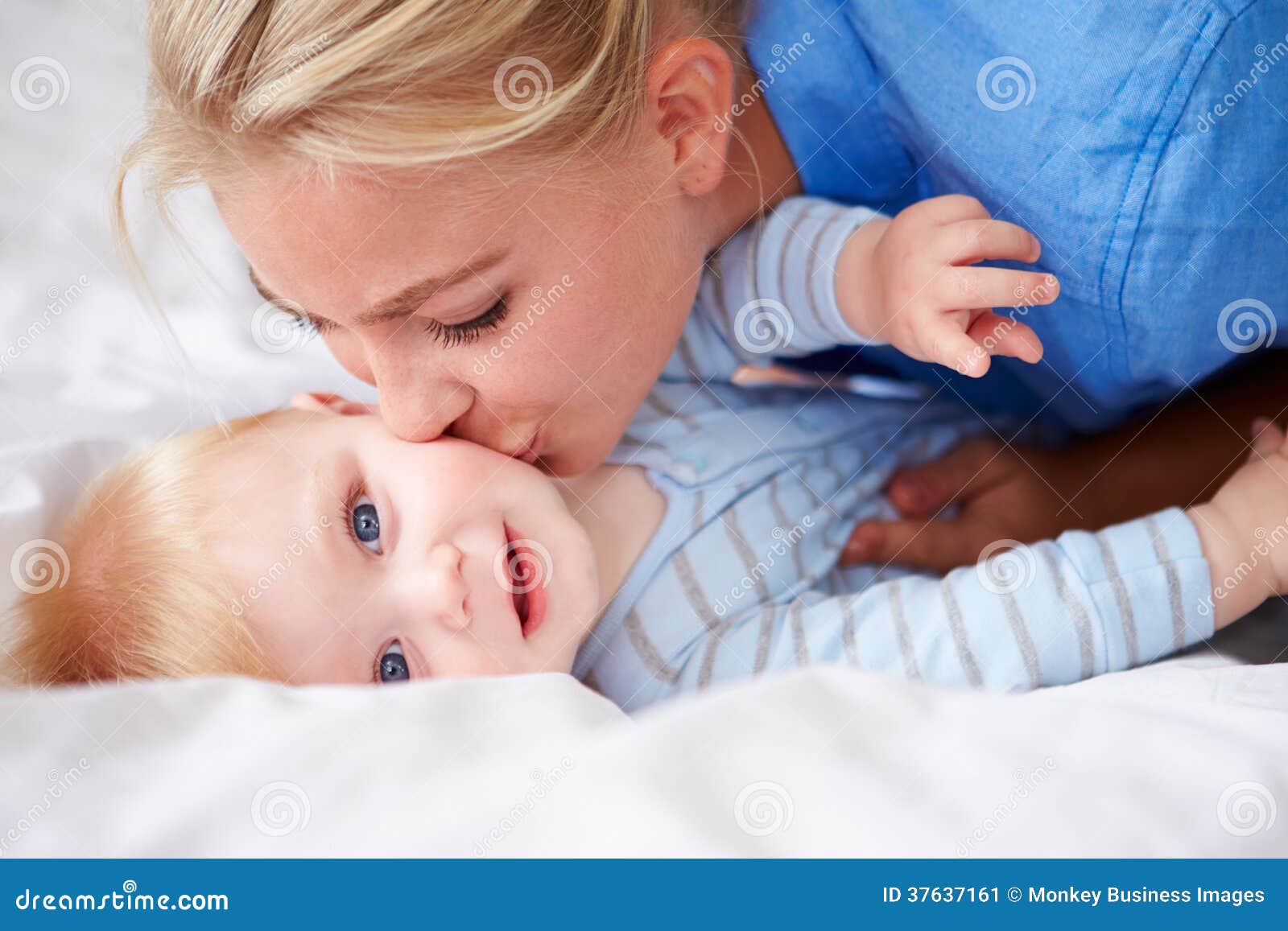 Mother Kissing Baby Son As They Lie In Bed Together Stock Image ...