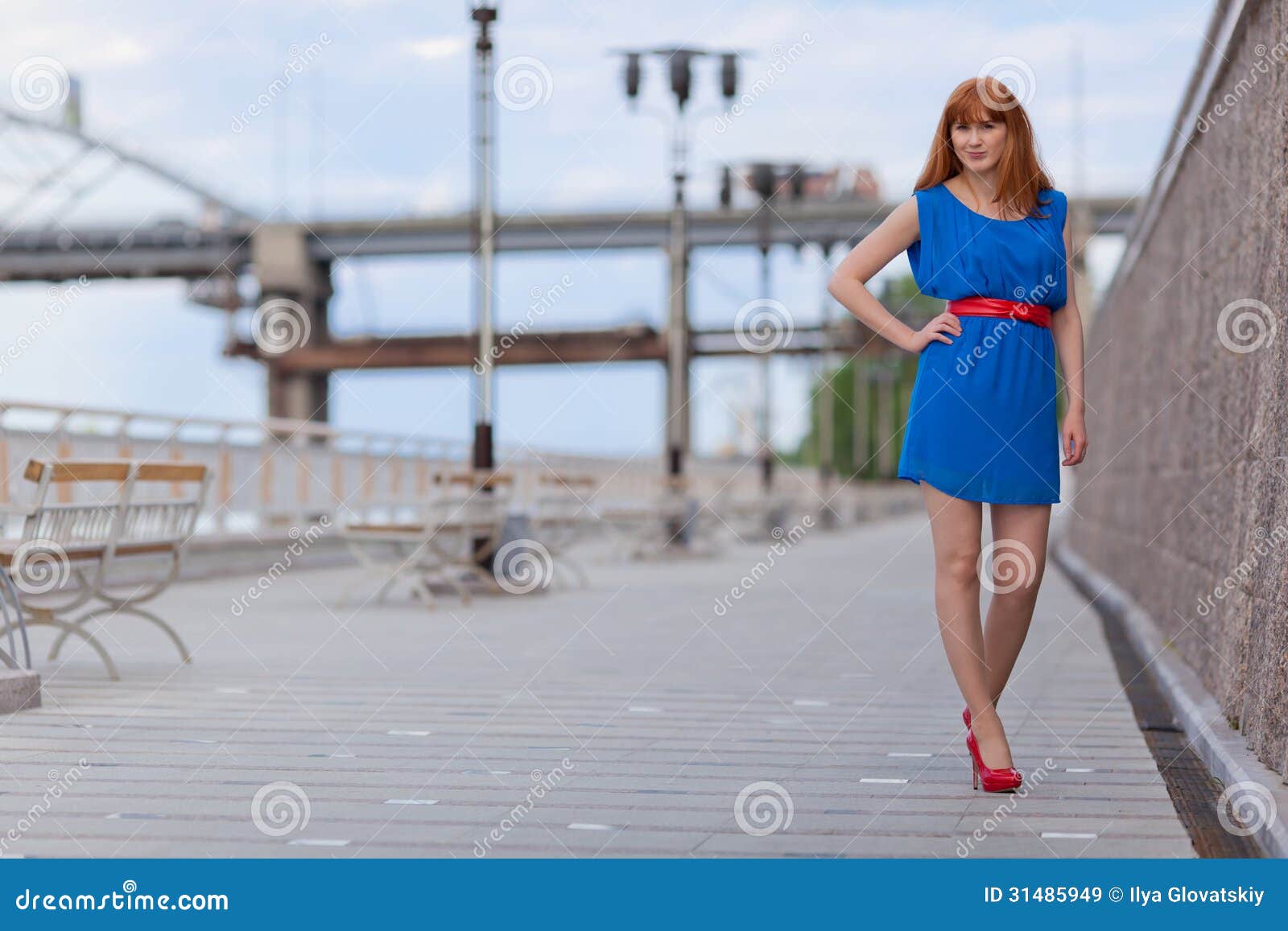 Mujer atractiva hermosa en vestido azul y zapatos rojos que camina ...