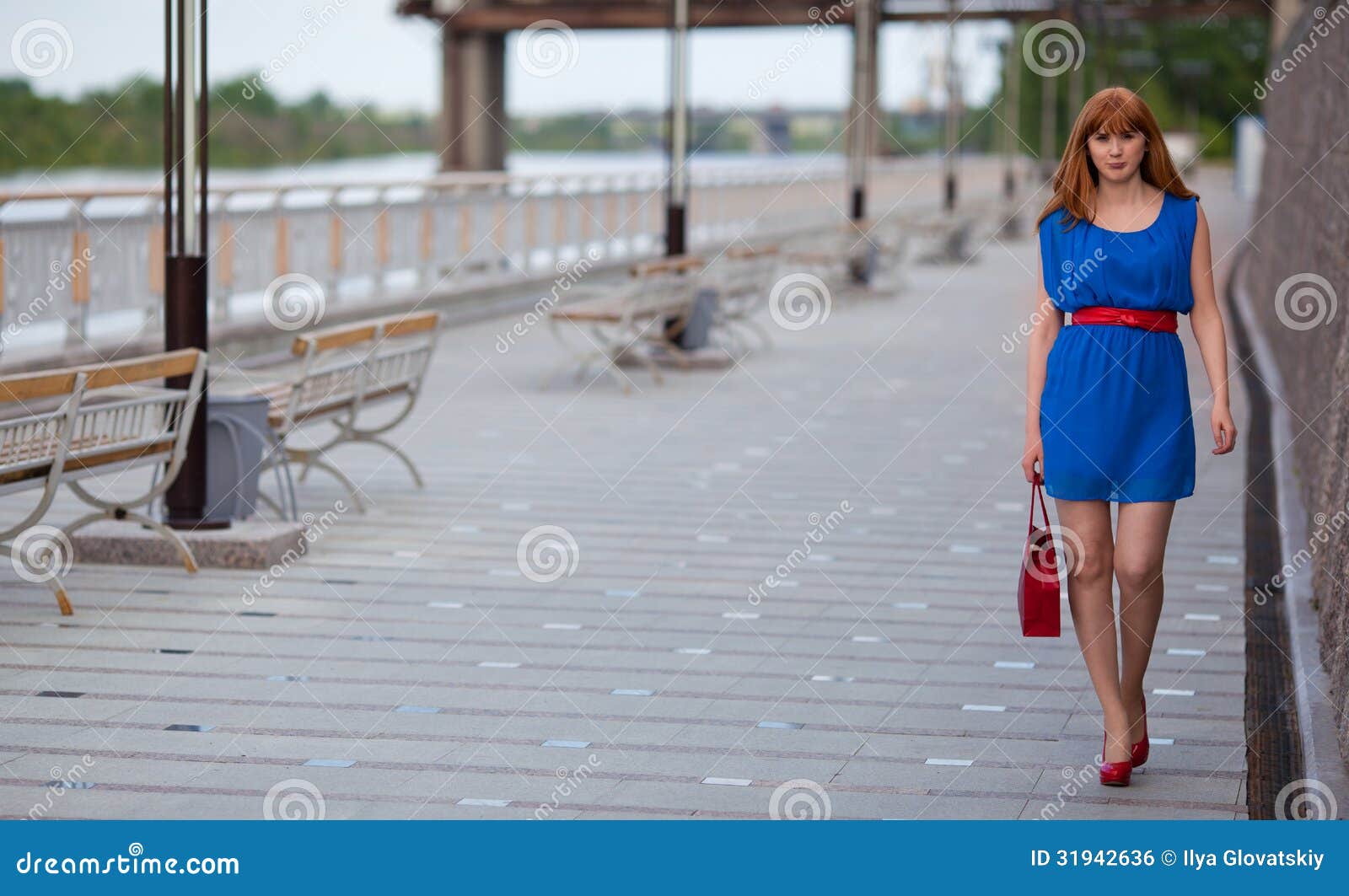 Mujer atractiva hermosa en vestido azul y zapatos rojos que camina ...